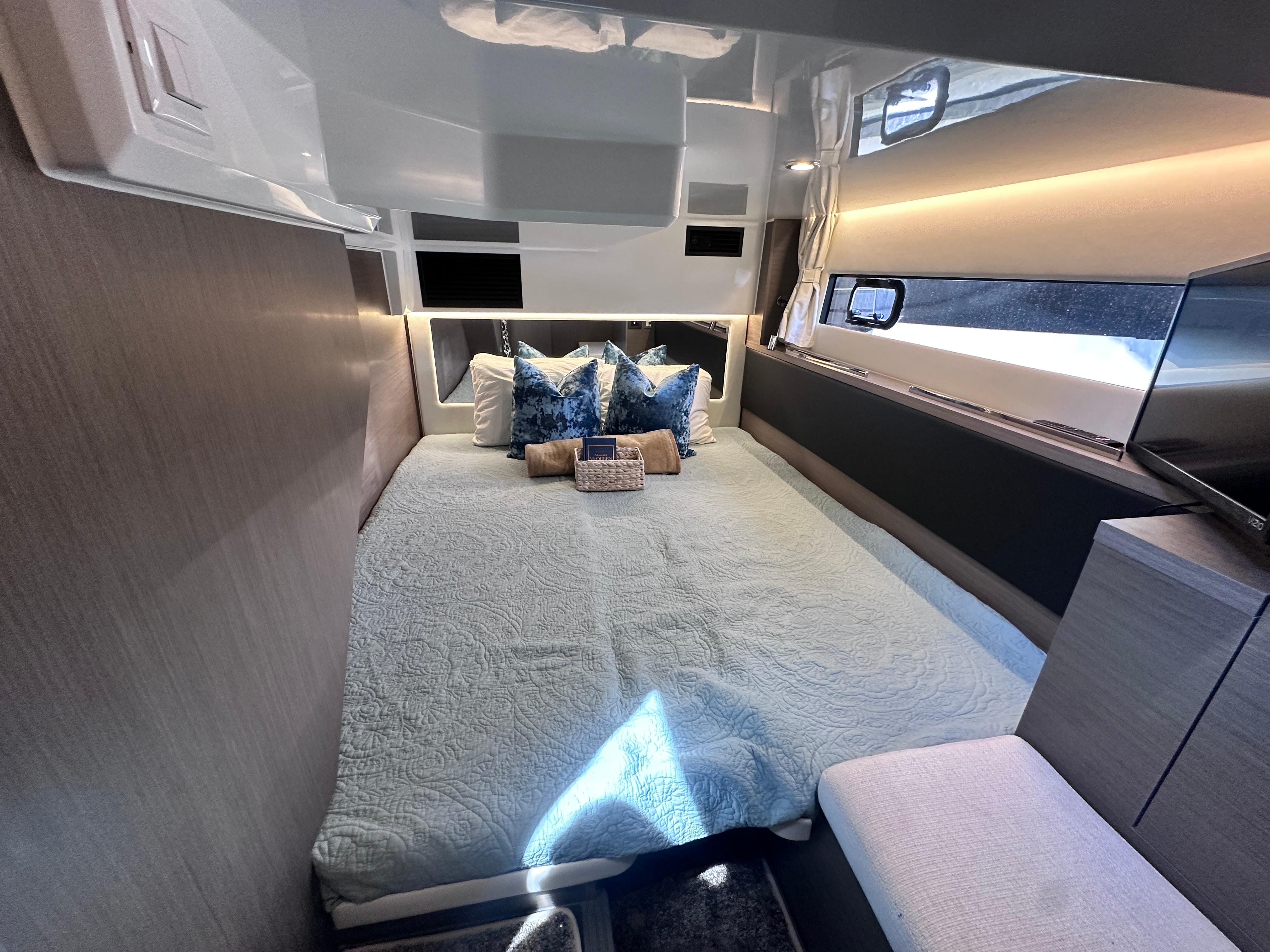 Luxurious interior cabin of 2025 Jeanneau 1295 yacht with modern bedding and ambient lighting.