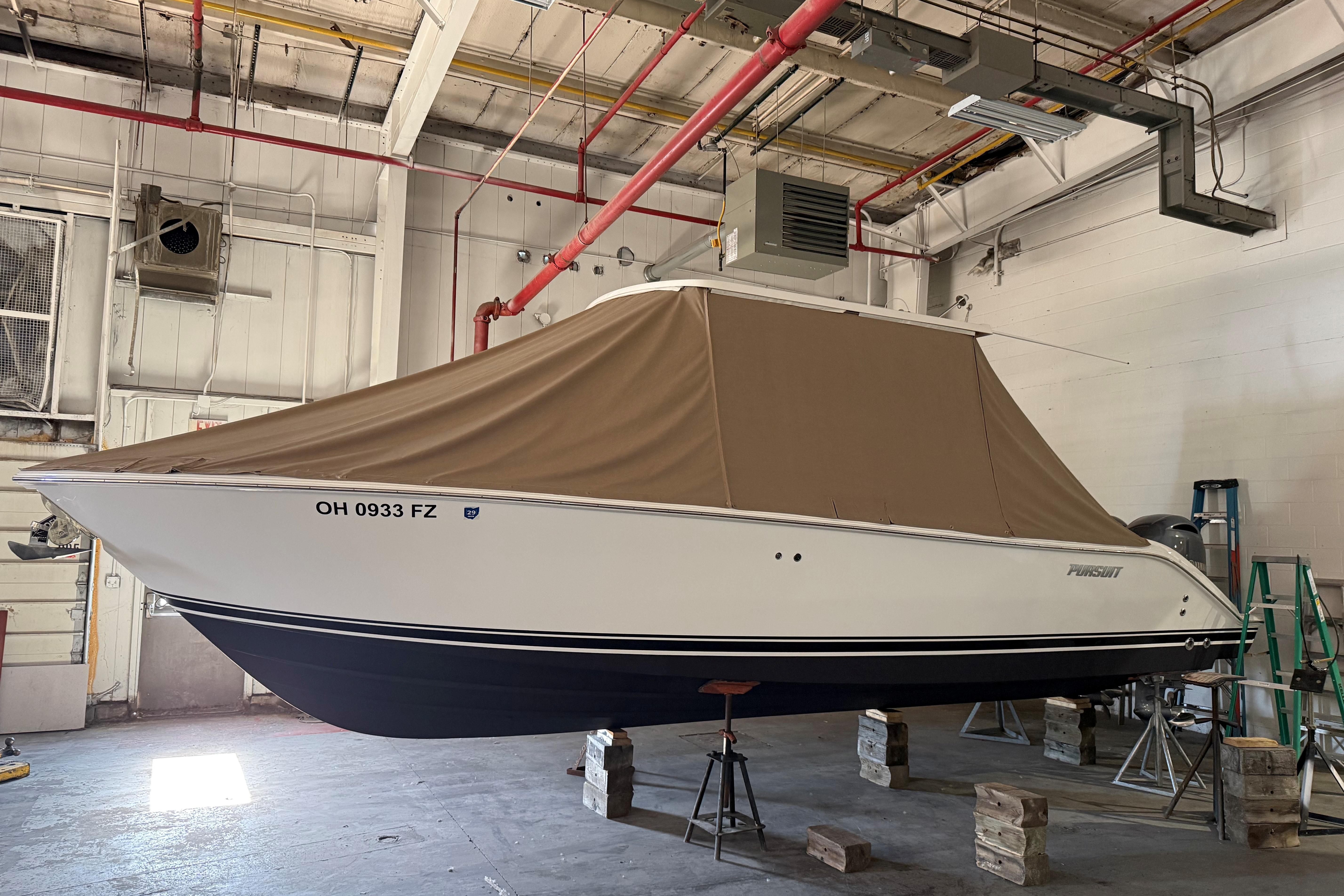 2021 Pursuit S 268 Sport boat in a garage, covered with a brown tarp.