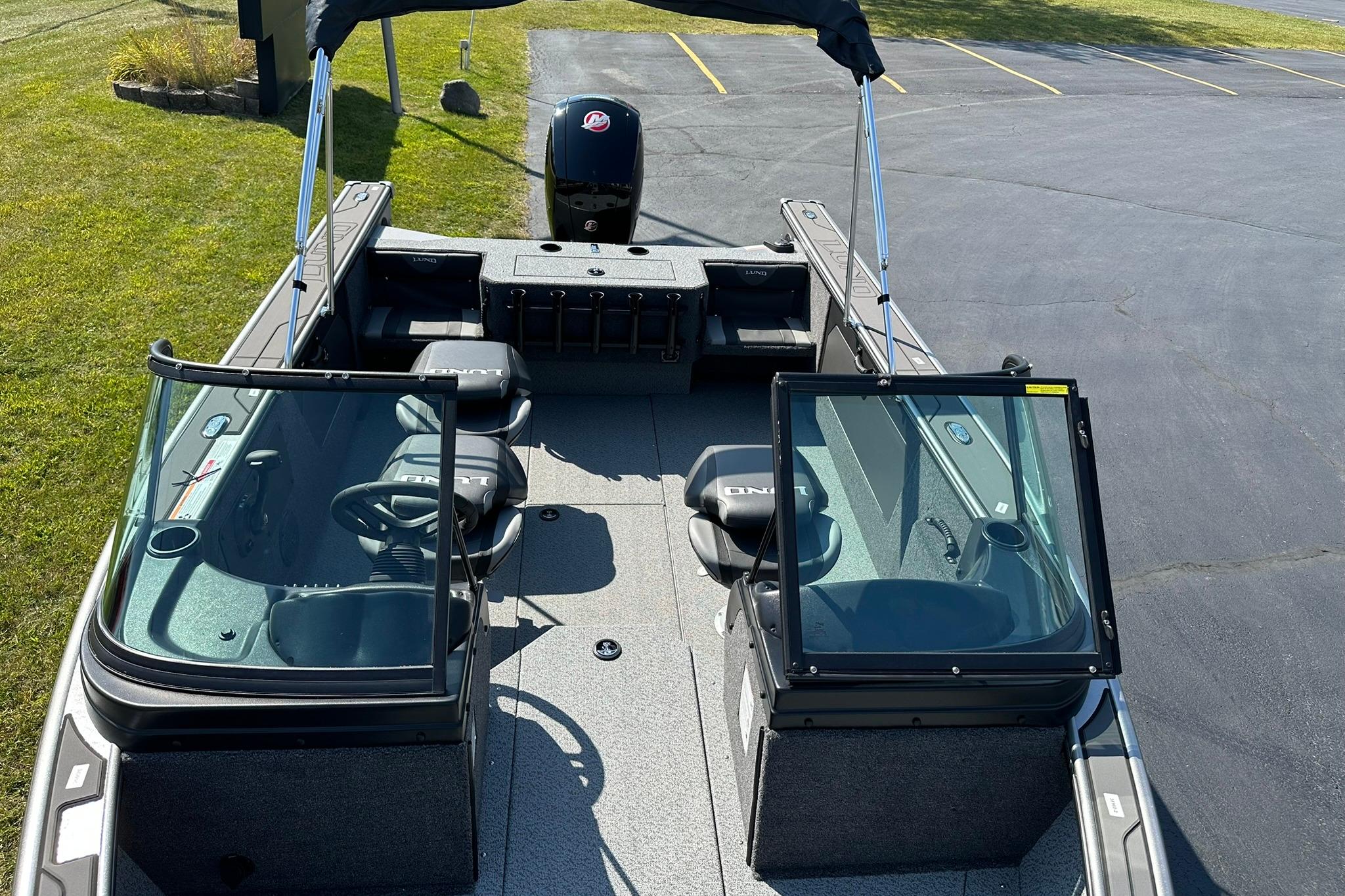 2026 Lund 1875 Fisherman boat interior with seating and windshield, parked on pavement.
