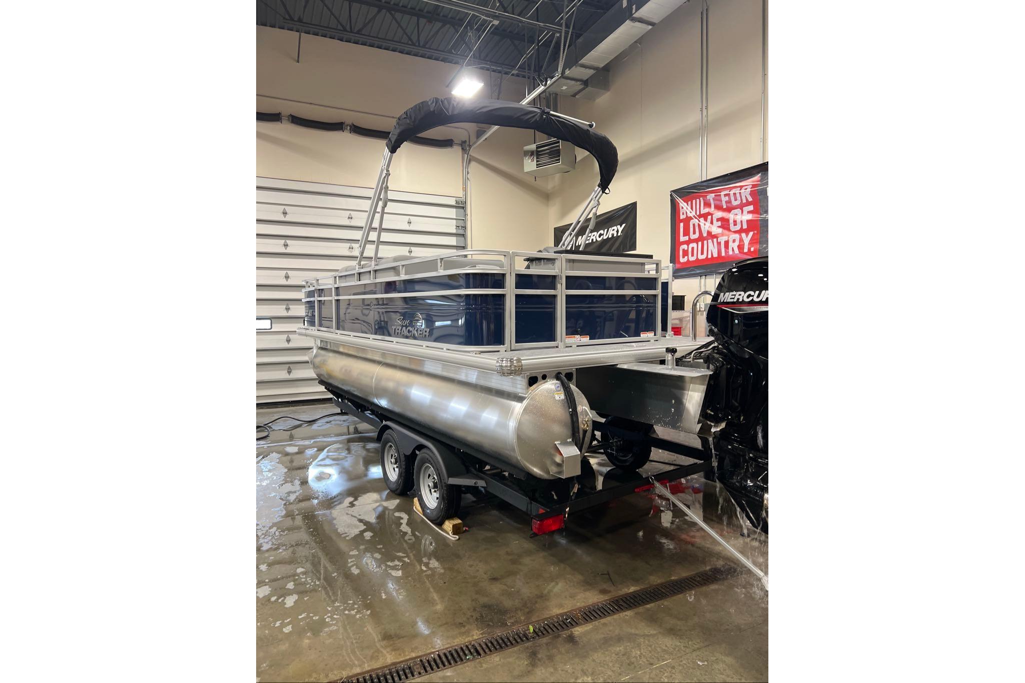 2026 Sun Tracker SportFish 20 DLX pontoon boat in a showroom, rear view.