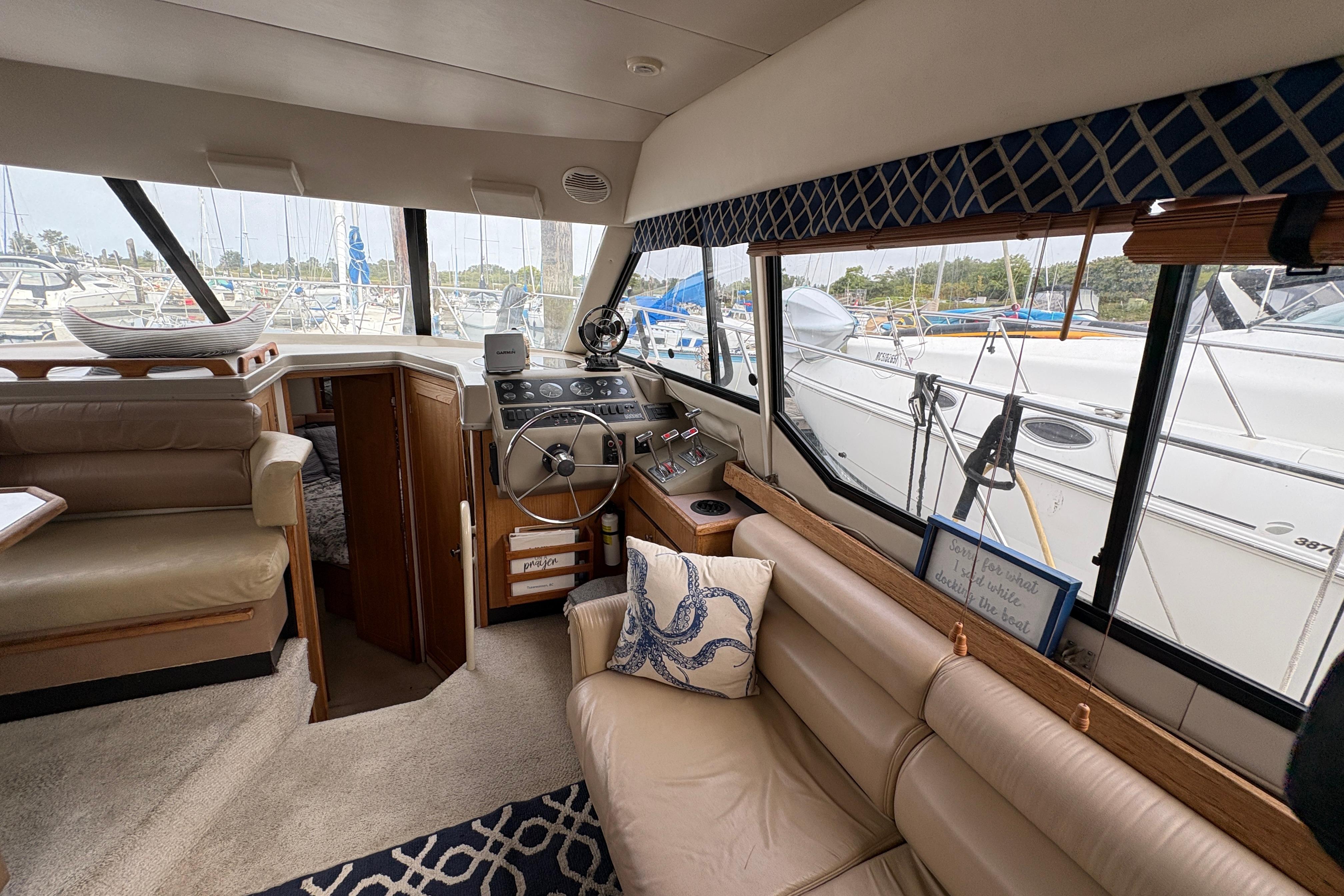 Interior of 1988 Bayliner 3587 Motoryacht with helm, seating, and marina view.