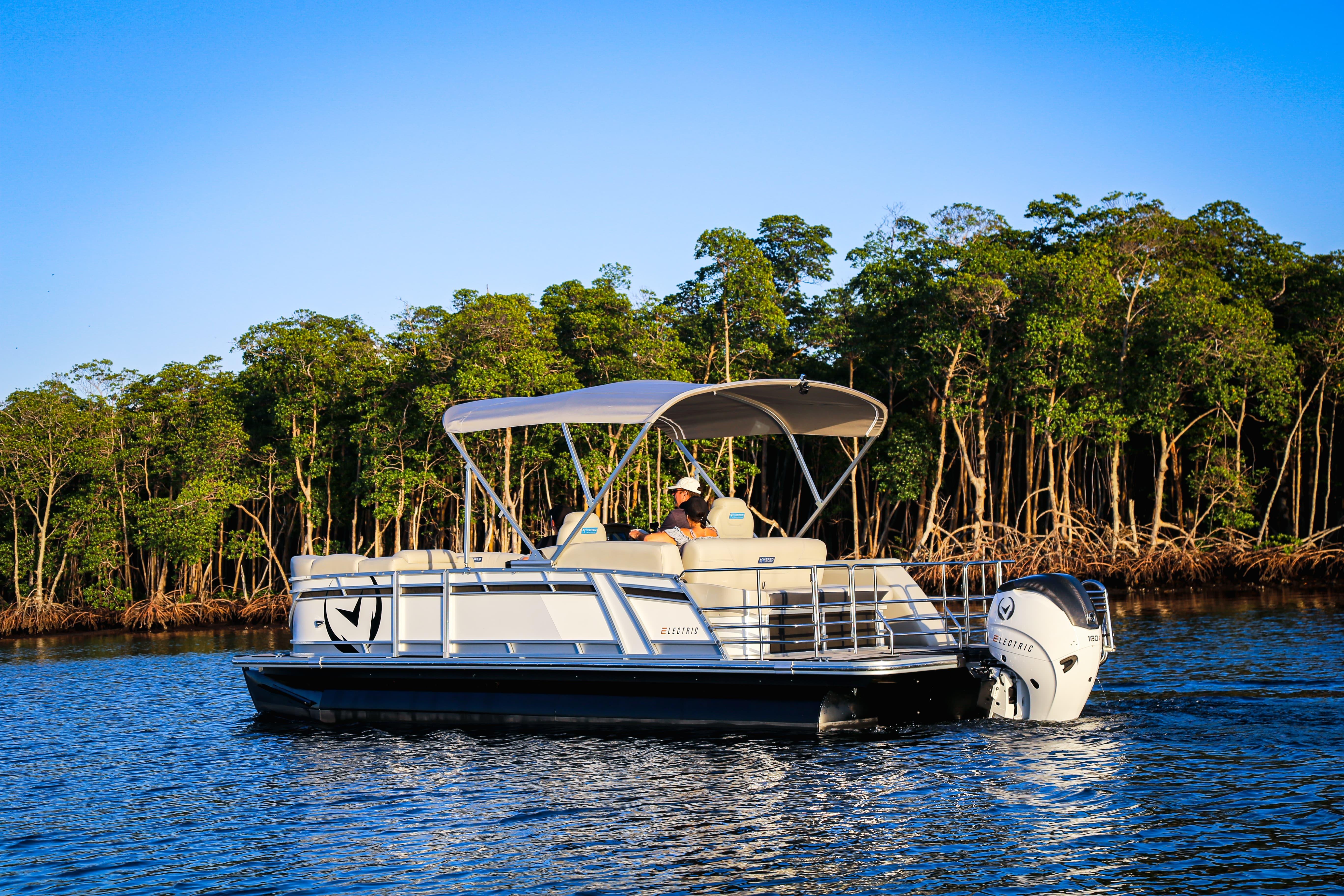 2025 Vision Marine Technologies V24 electric boat cruising on a serene lake.