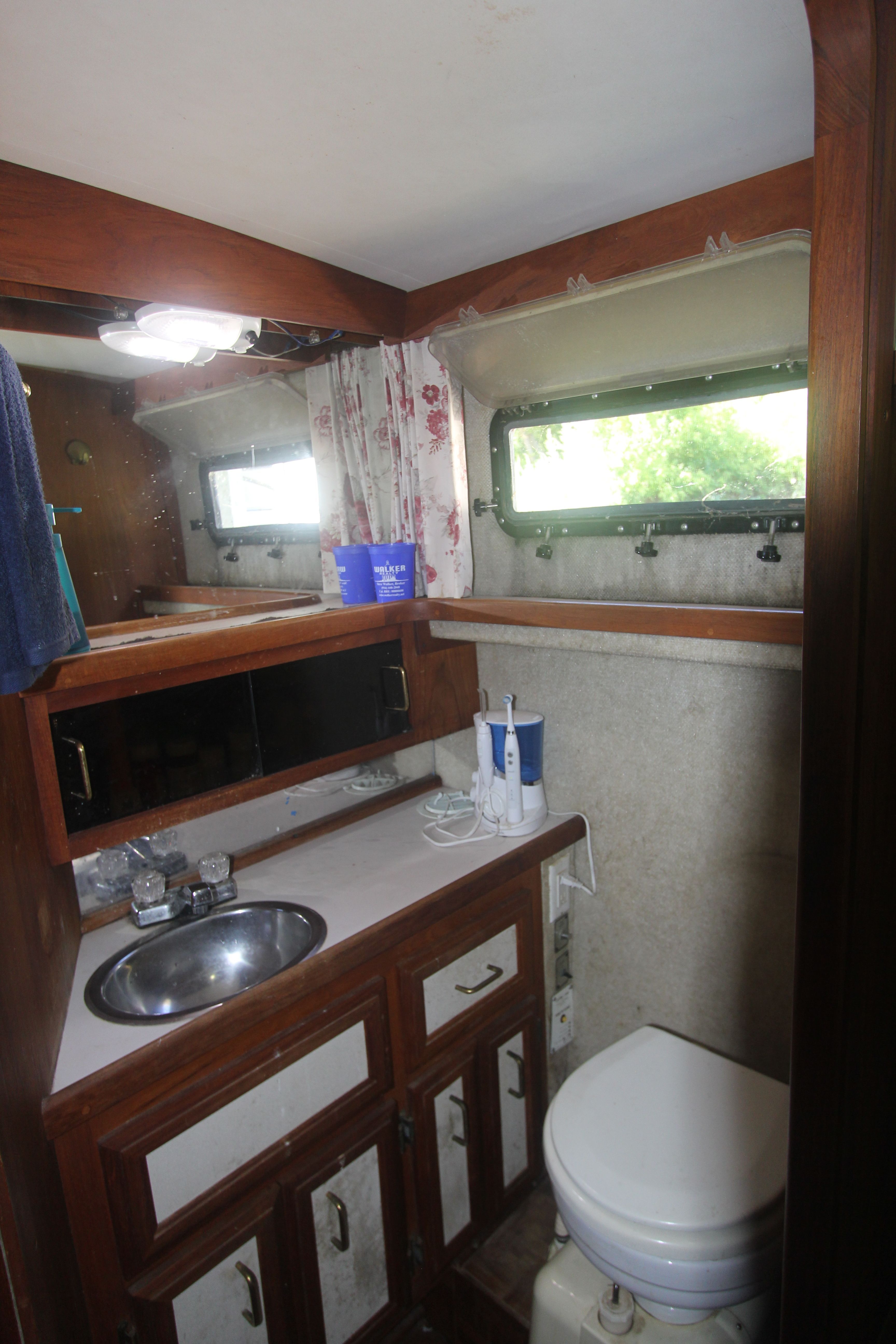 Interior view of a yacht bathroom with sink, toilet, and mirror.