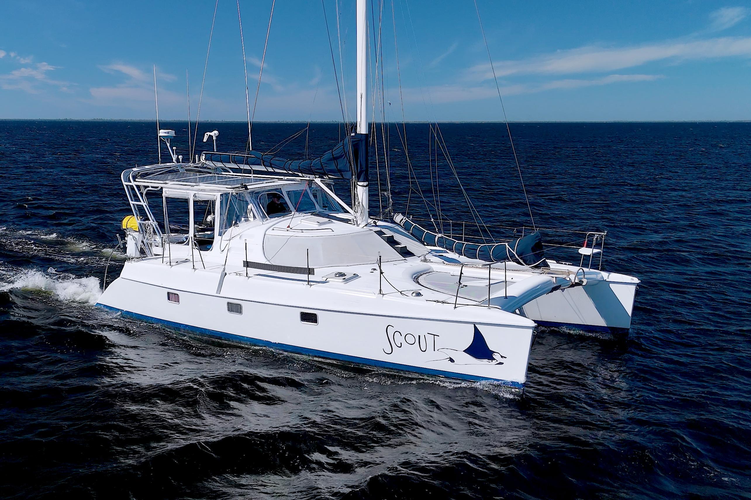 1998 Manta 40 catamaran sailing on open sea under clear blue sky.