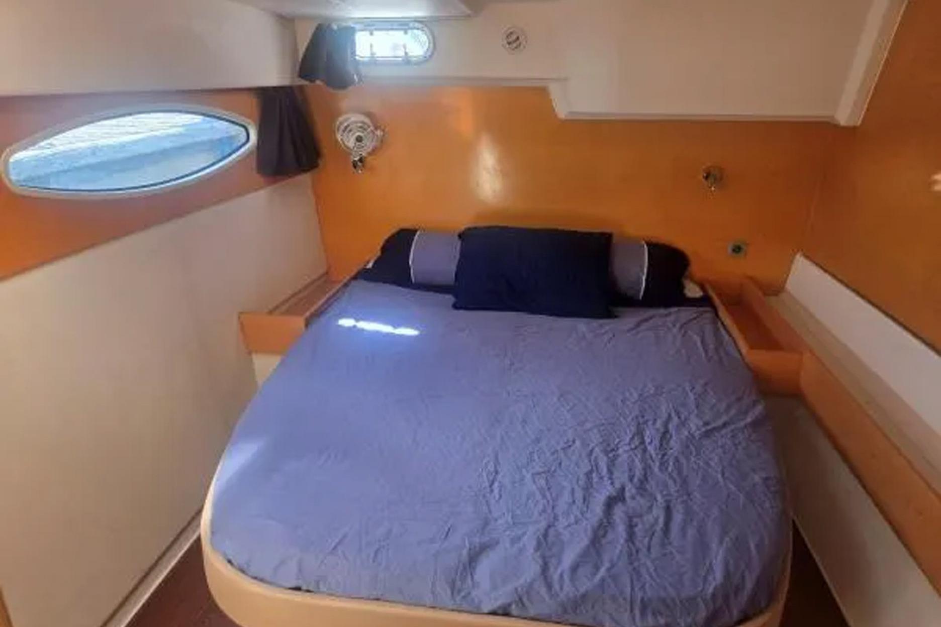 Cozy cabin interior of 2008 Fountaine Pajot Salina 48 catamaran with bed and porthole window.