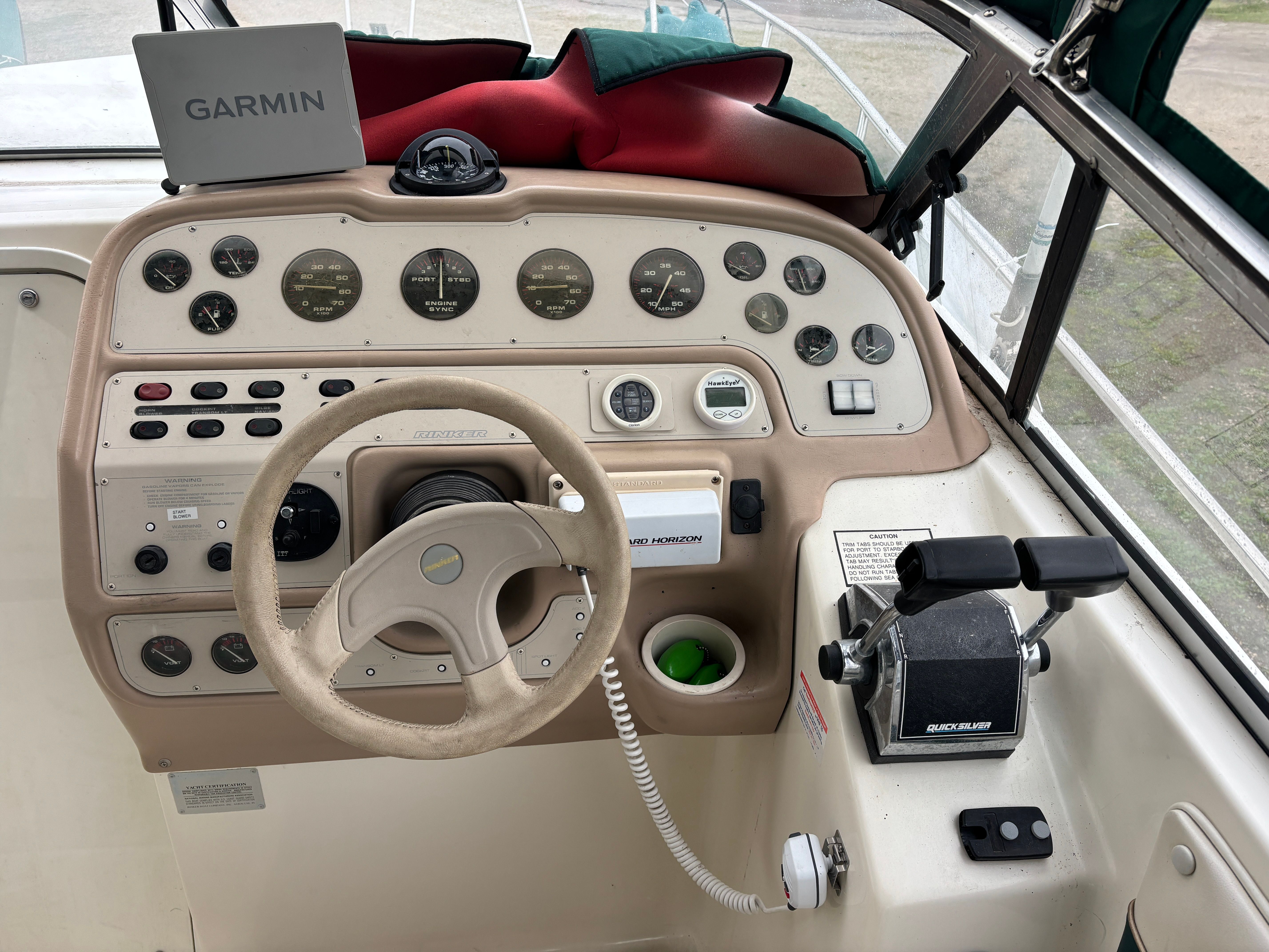 The cockpit of a Rinker Fiesta Vee 280 with steering wheel, instruments, and Garmin device.