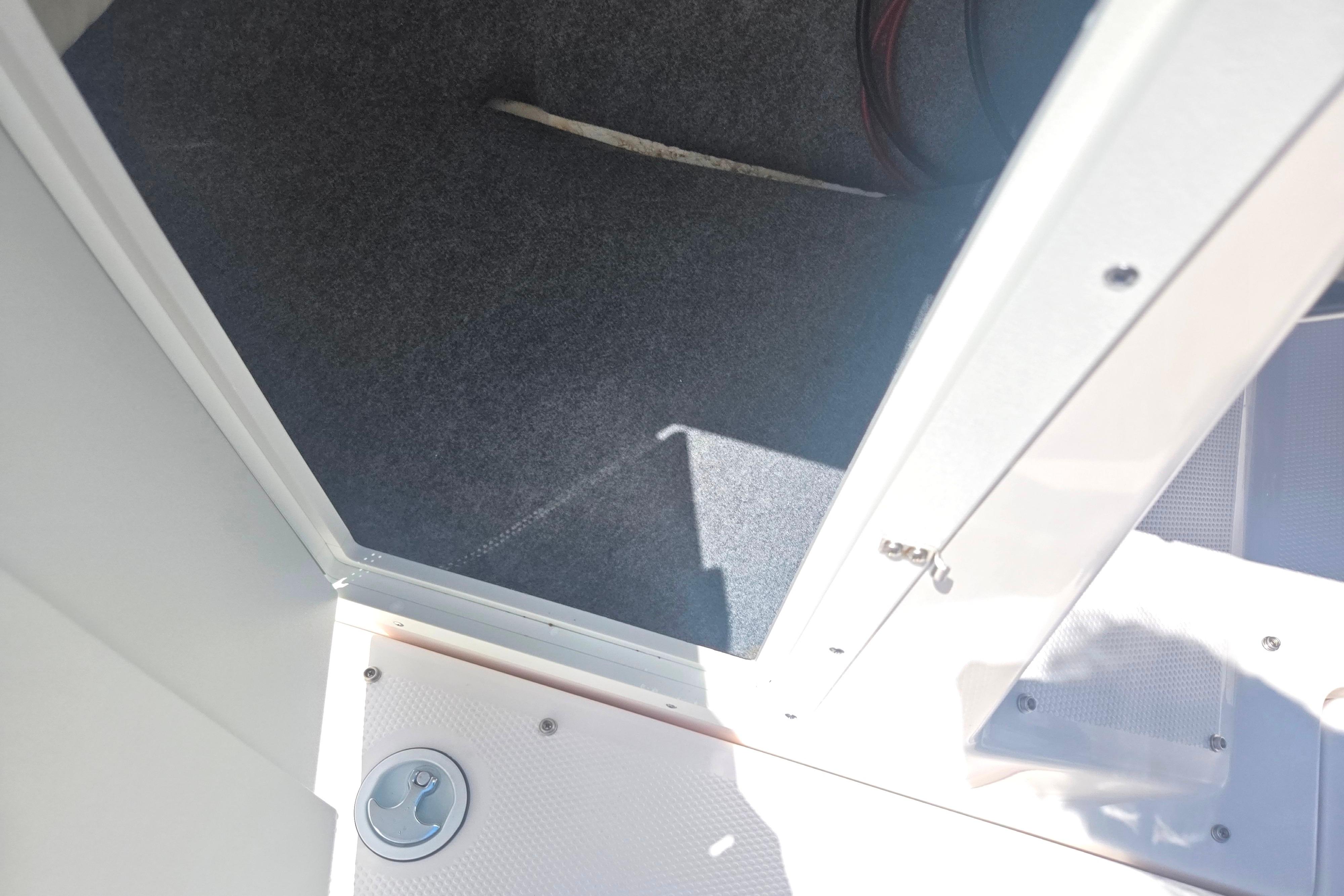Interior storage compartment of 2023 Yamaha Boats SX220, featuring carpeted flooring and secure latch.