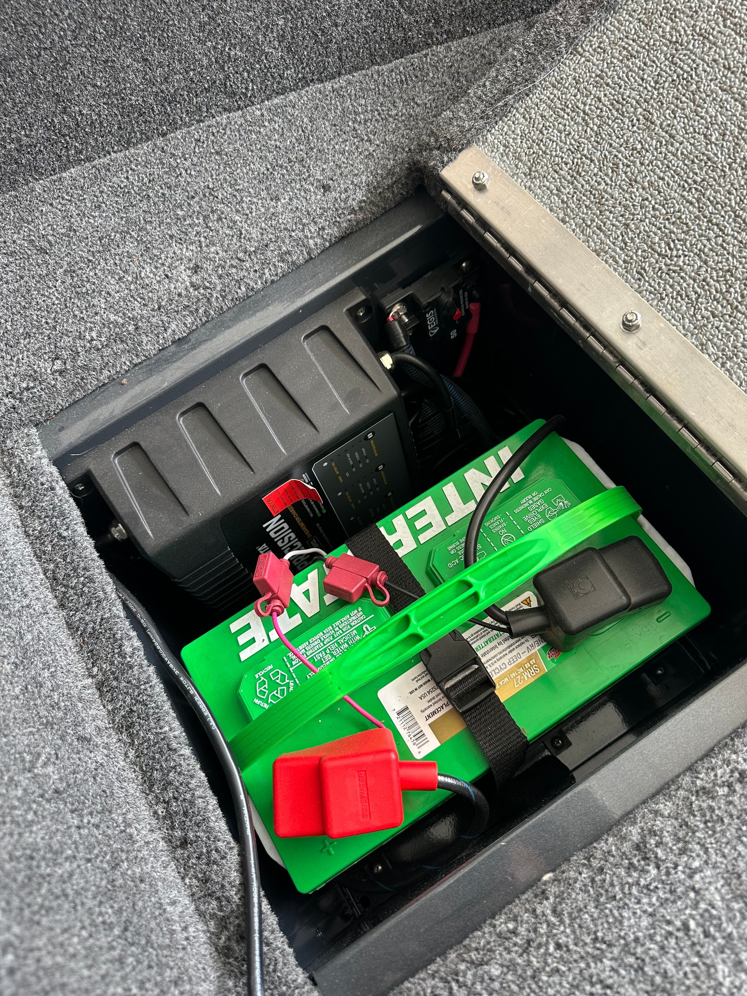 Battery compartment of a 2025 Lund Pro Angler 1650 with a green battery and wiring.