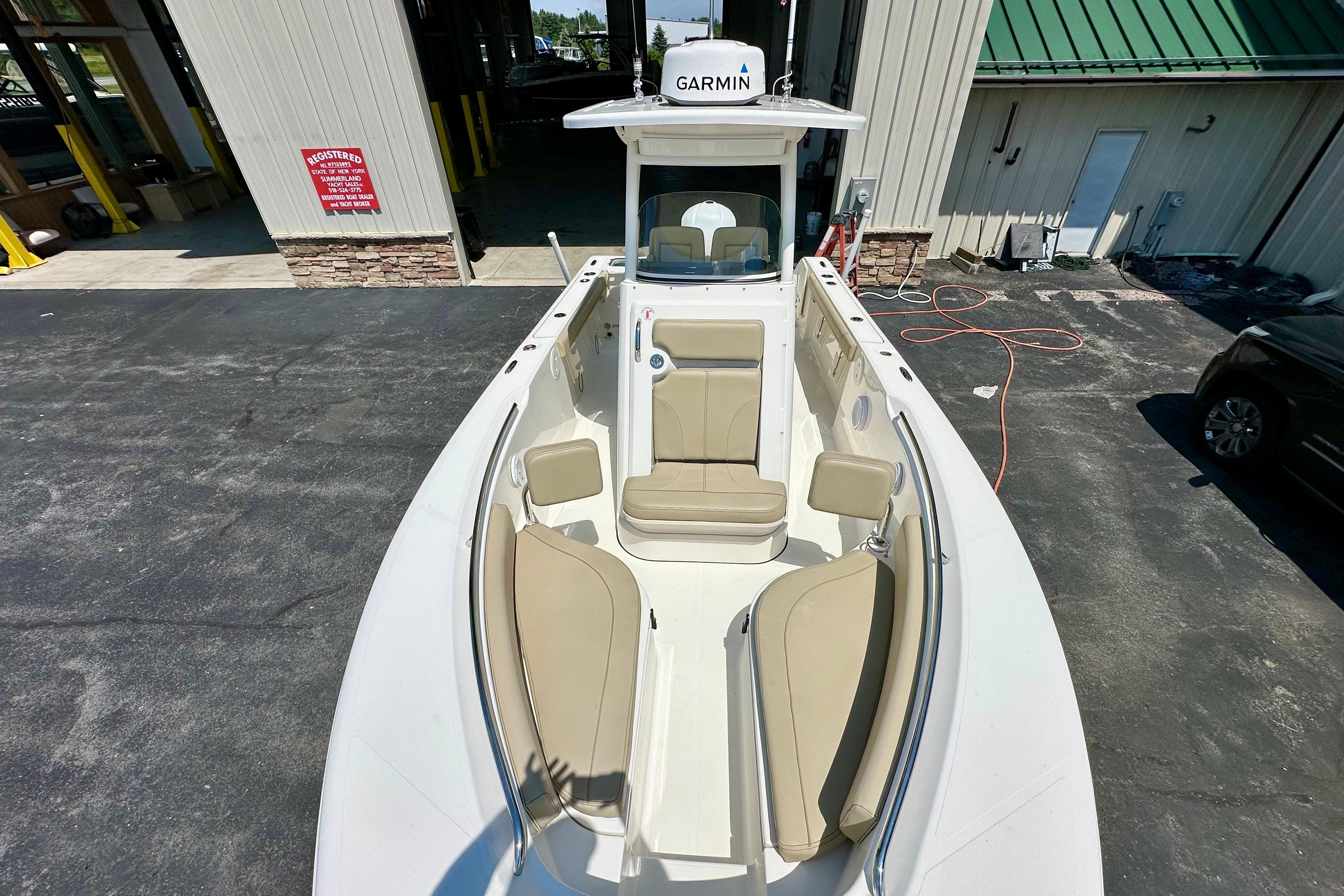 2020 Pursuit C 238 Center Console boat with beige seating, docked near a building.