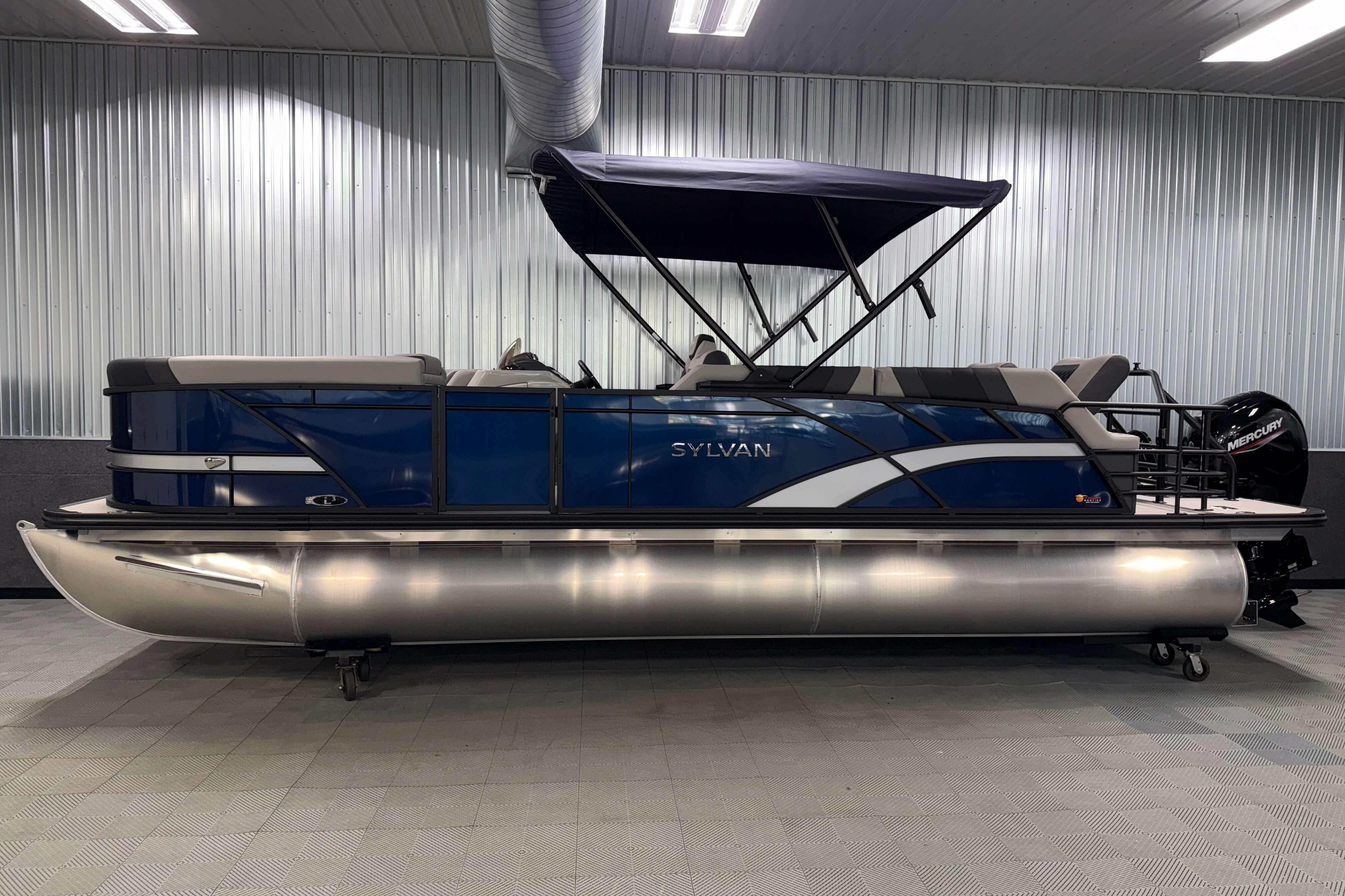 2026 Sylvan L3 SLZ pontoon boat with blue exterior and canopy in showroom.