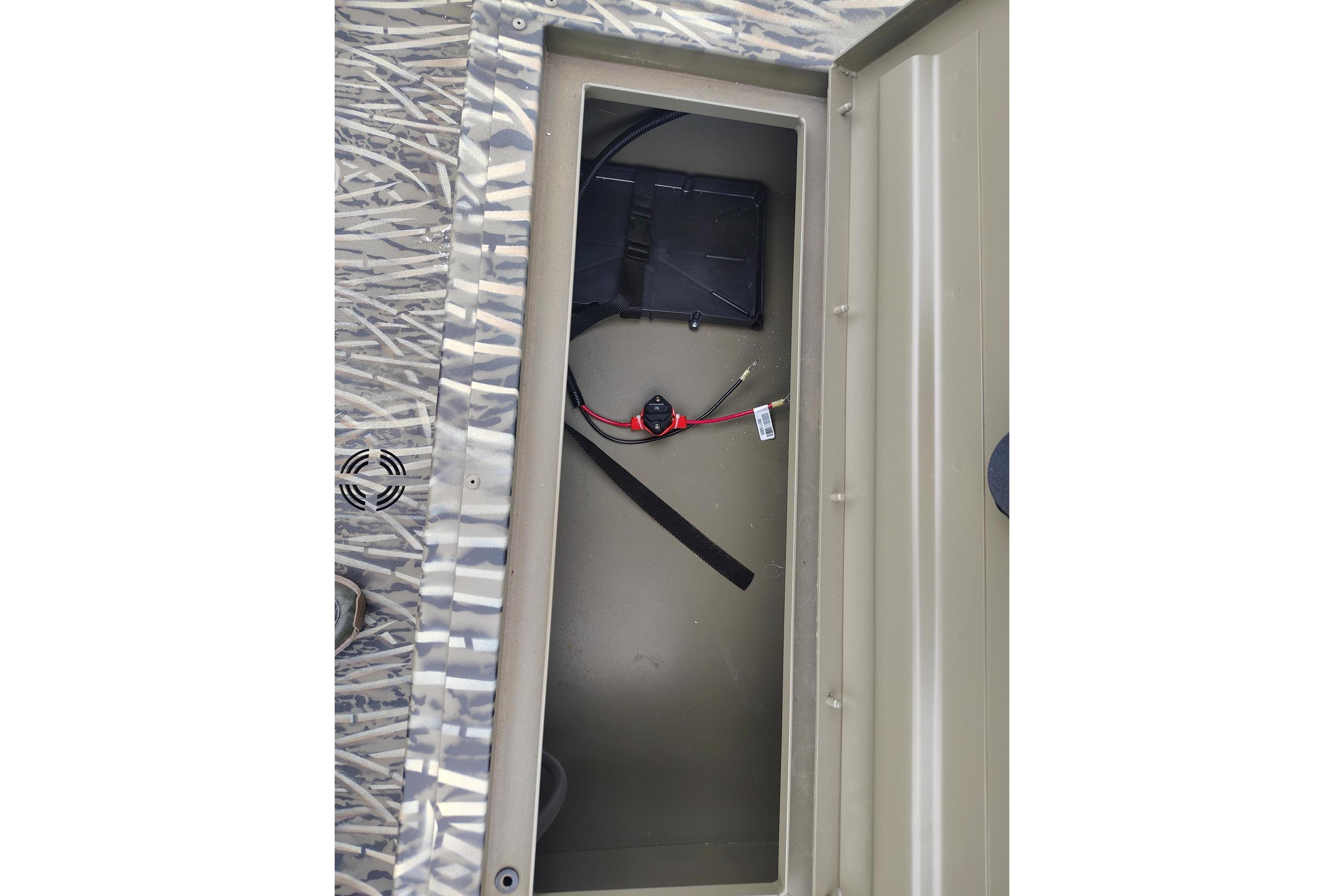 2026 Tracker Grizzly 1754 SC boat storage compartment with wiring and battery holder.