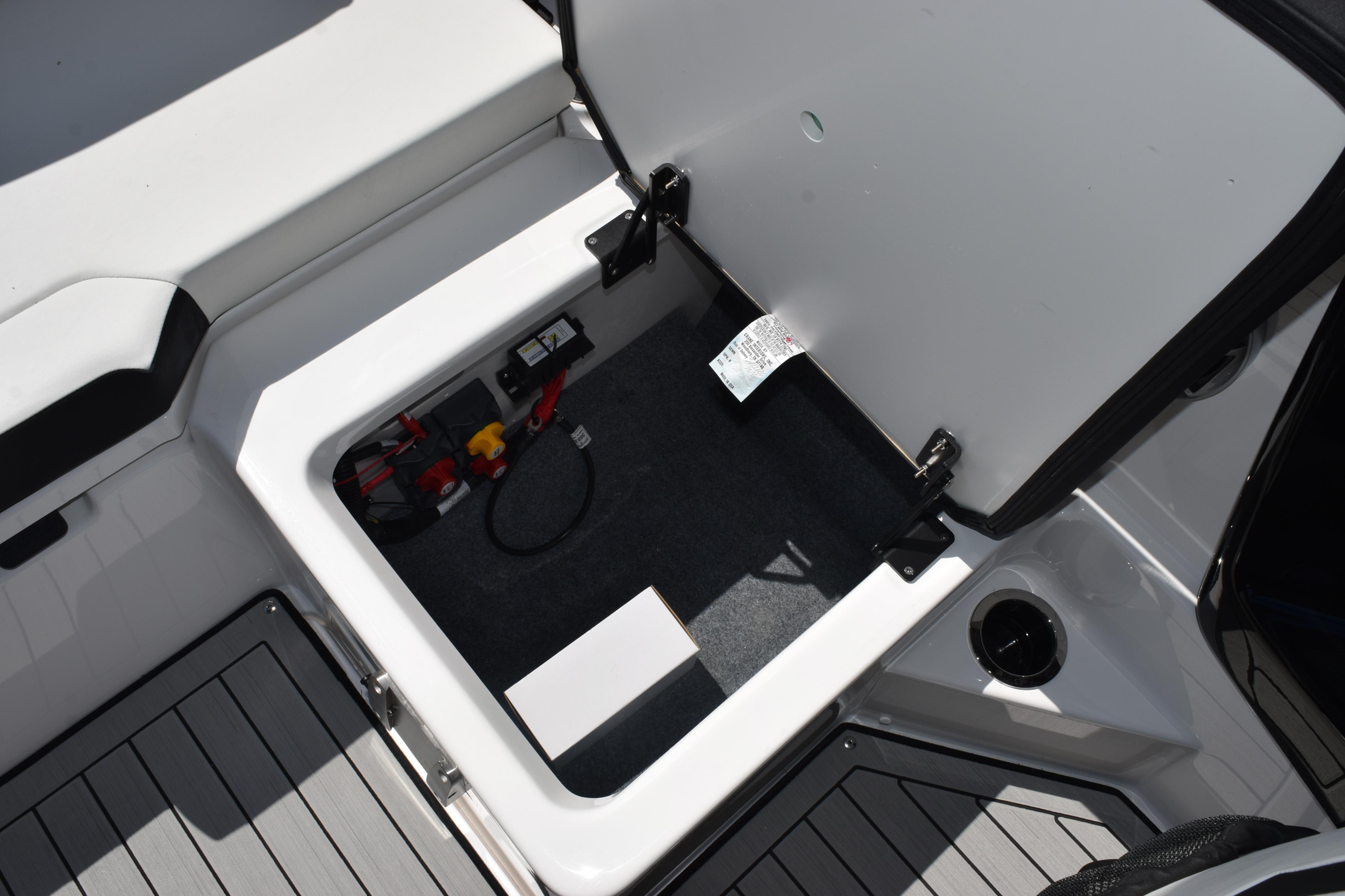 Open storage compartment in 2026 Yamaha Boats 222SE, showcasing interior features and battery setup.