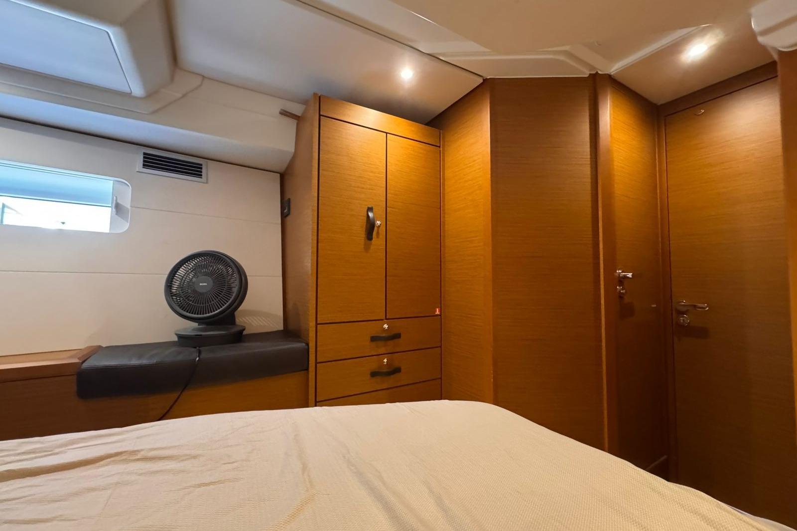 Interior cabin of 2018 Jeanneau 54 yacht with wooden cabinetry and a small fan.
