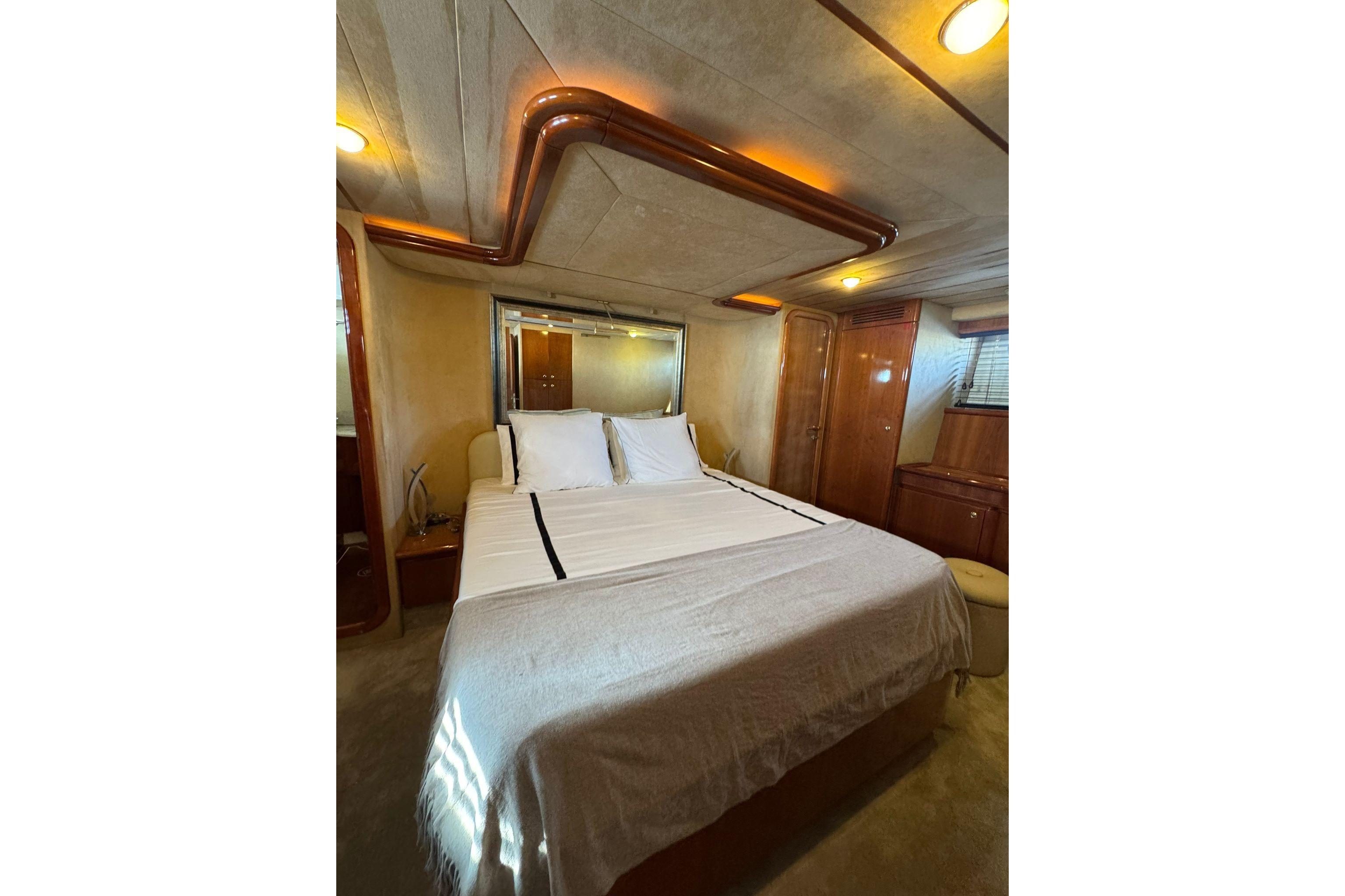 Luxurious bedroom interior of 2005 Ferretti Yachts 680 with elegant wood finishes.