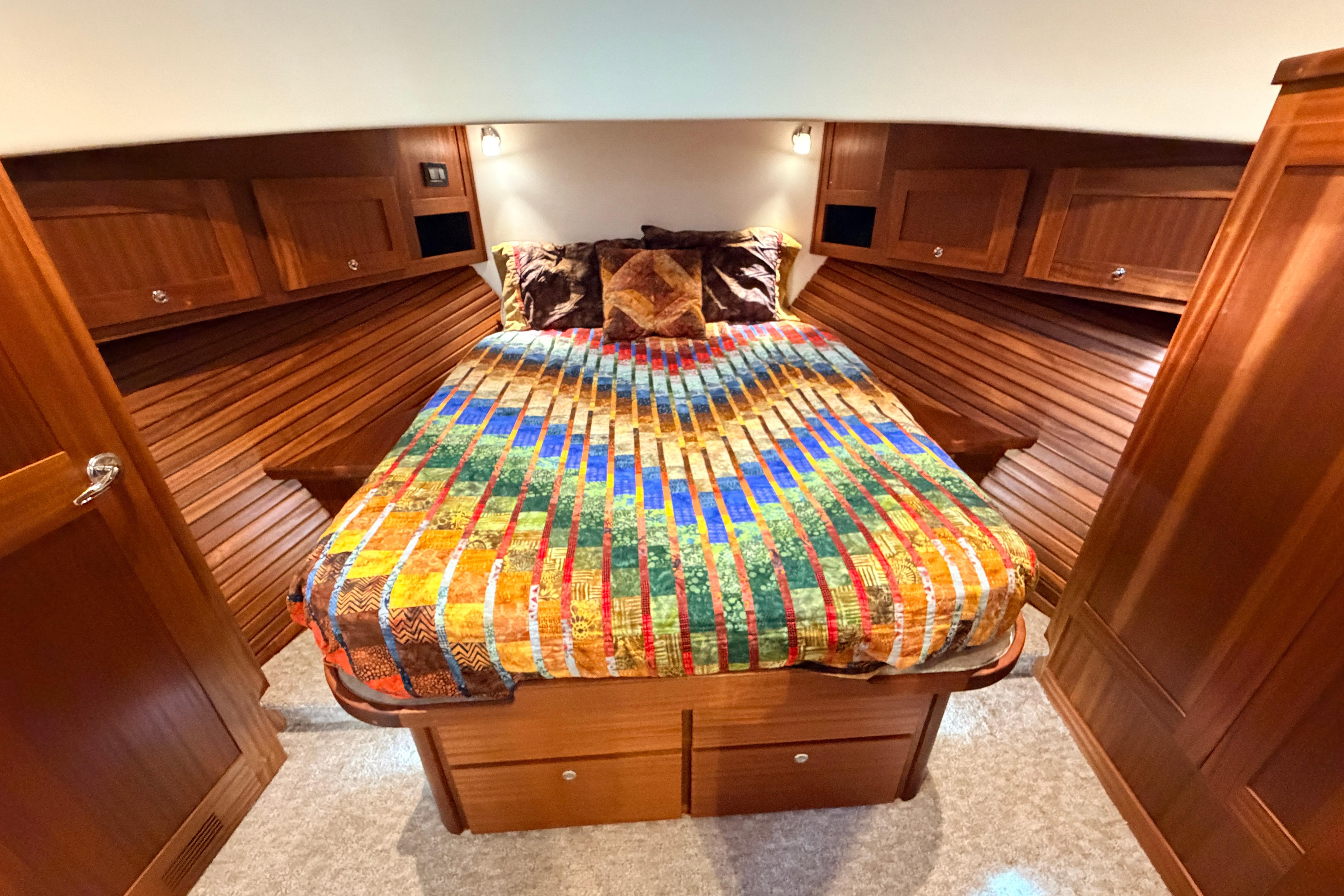 Cozy cabin interior of 2022 American Tug 365 with colorful bedding and wooden cabinetry.