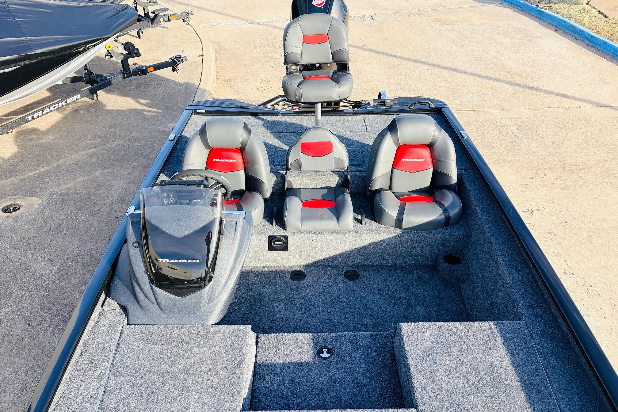 2025 Tracker Savage 215 boat interior with gray and red seating, steering console, and carpeted floor.