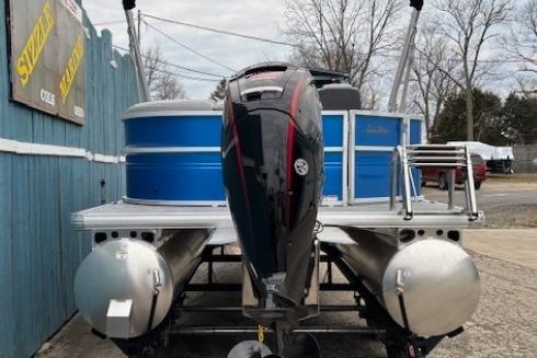 2026 Sun Tracker Party Barge 20 DLX pontoon boat with outboard motor, docked outdoors.