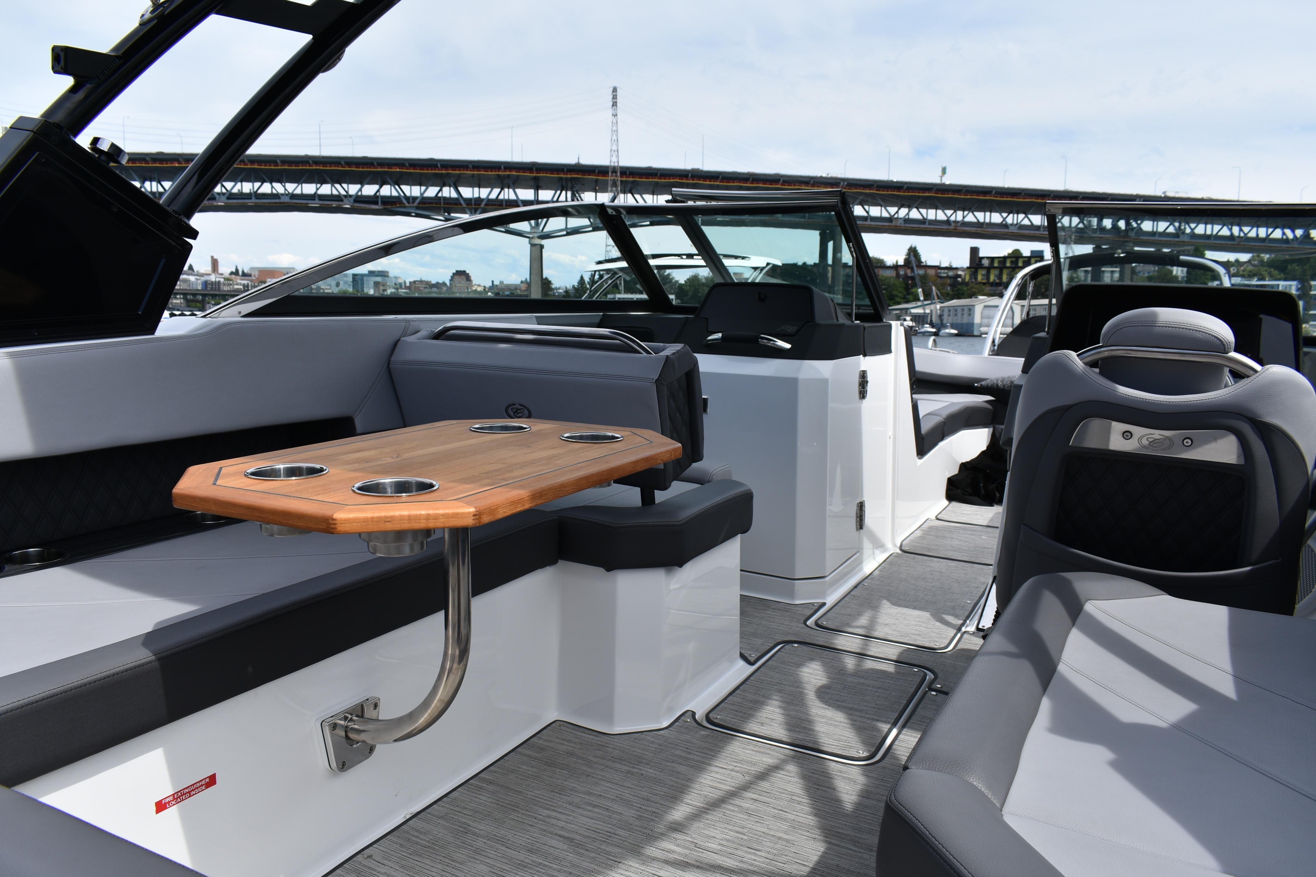 2023 Cobalt R8 boat interior with seating and wooden table, under a bridge.