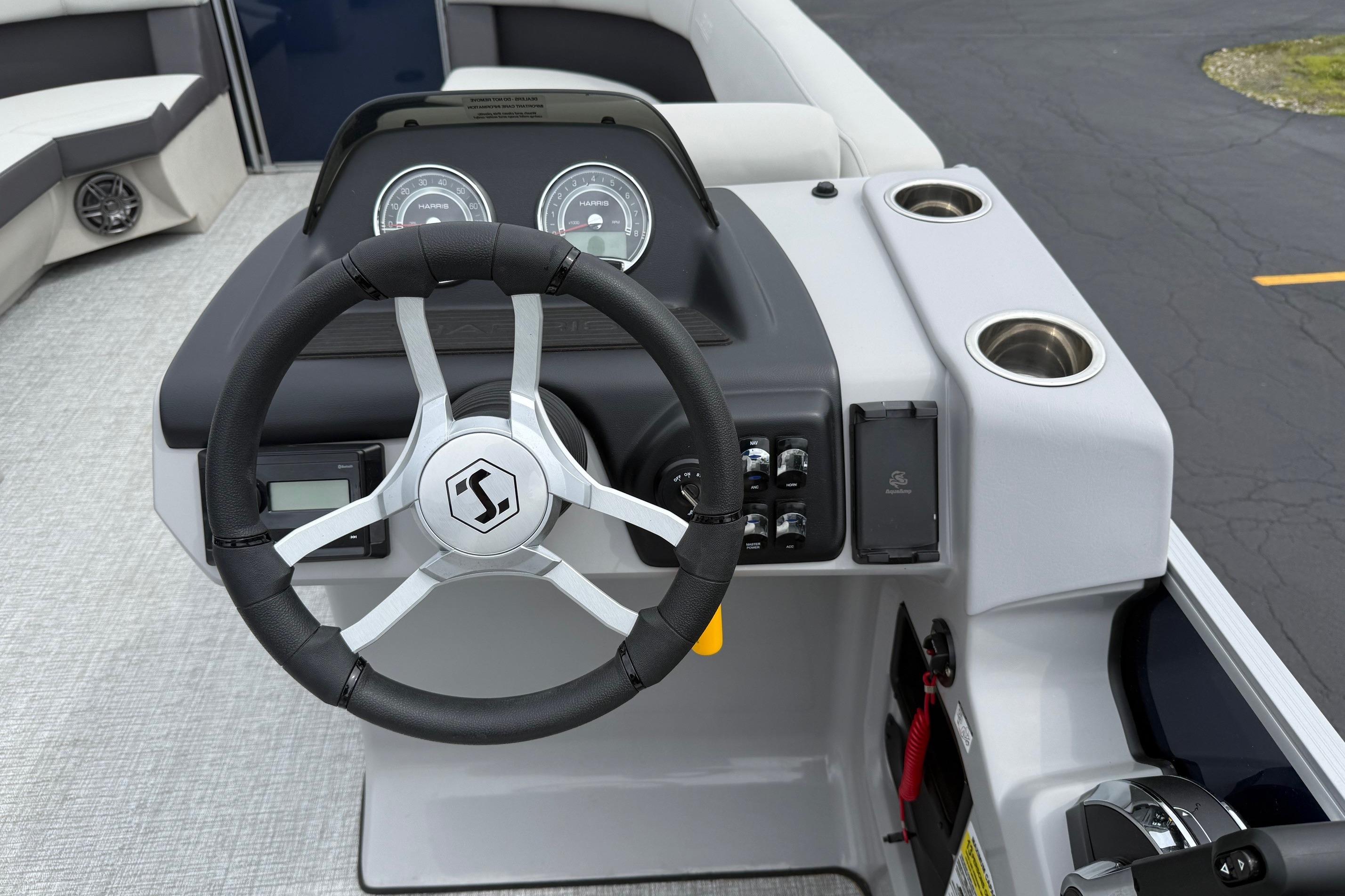 Steering console of 2025 Harris Cruiser 230 pontoon boat with modern controls and cup holders.