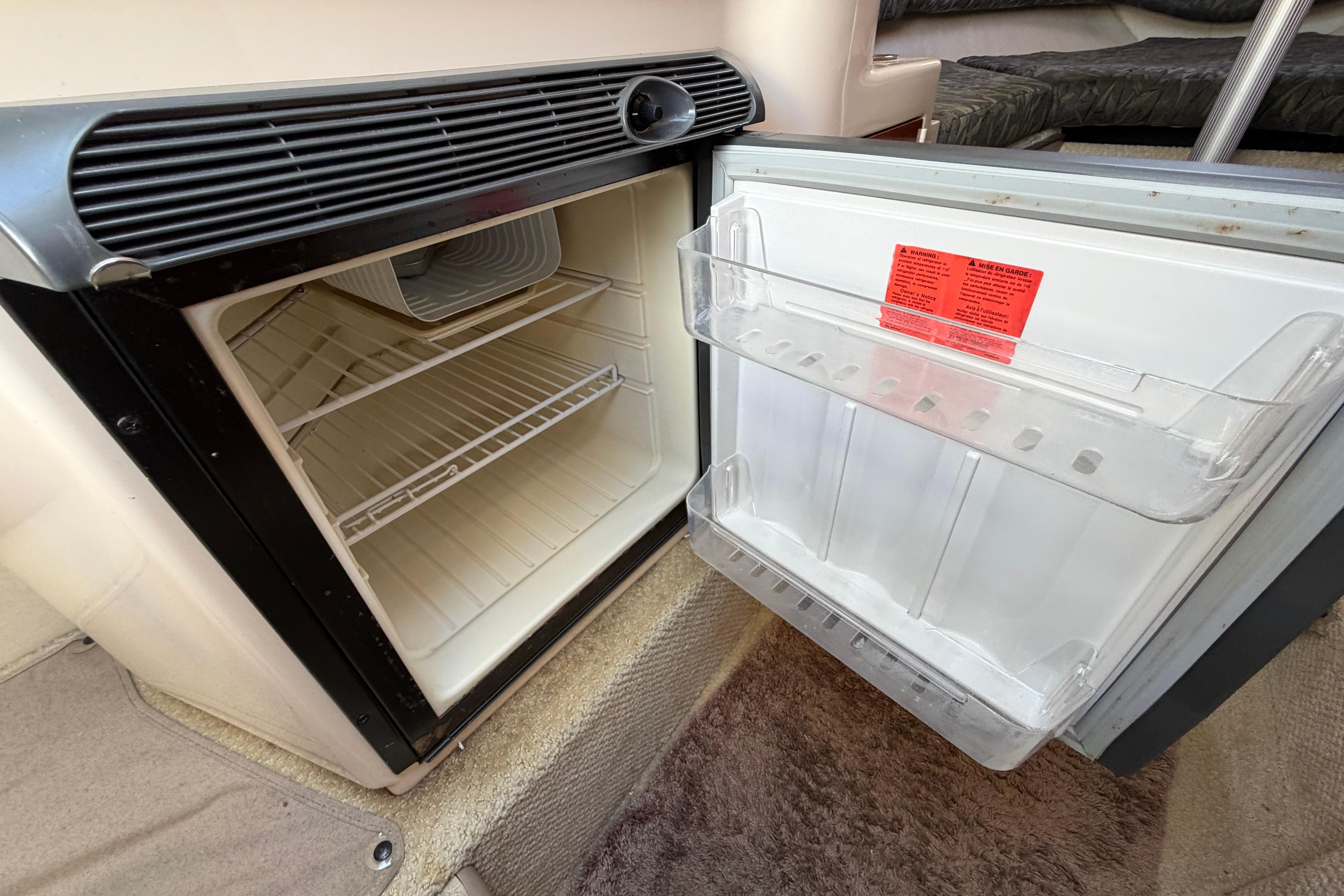 Open refrigerator inside a 2004 Sea Ray Sundancer 260 boat, showing empty shelves.