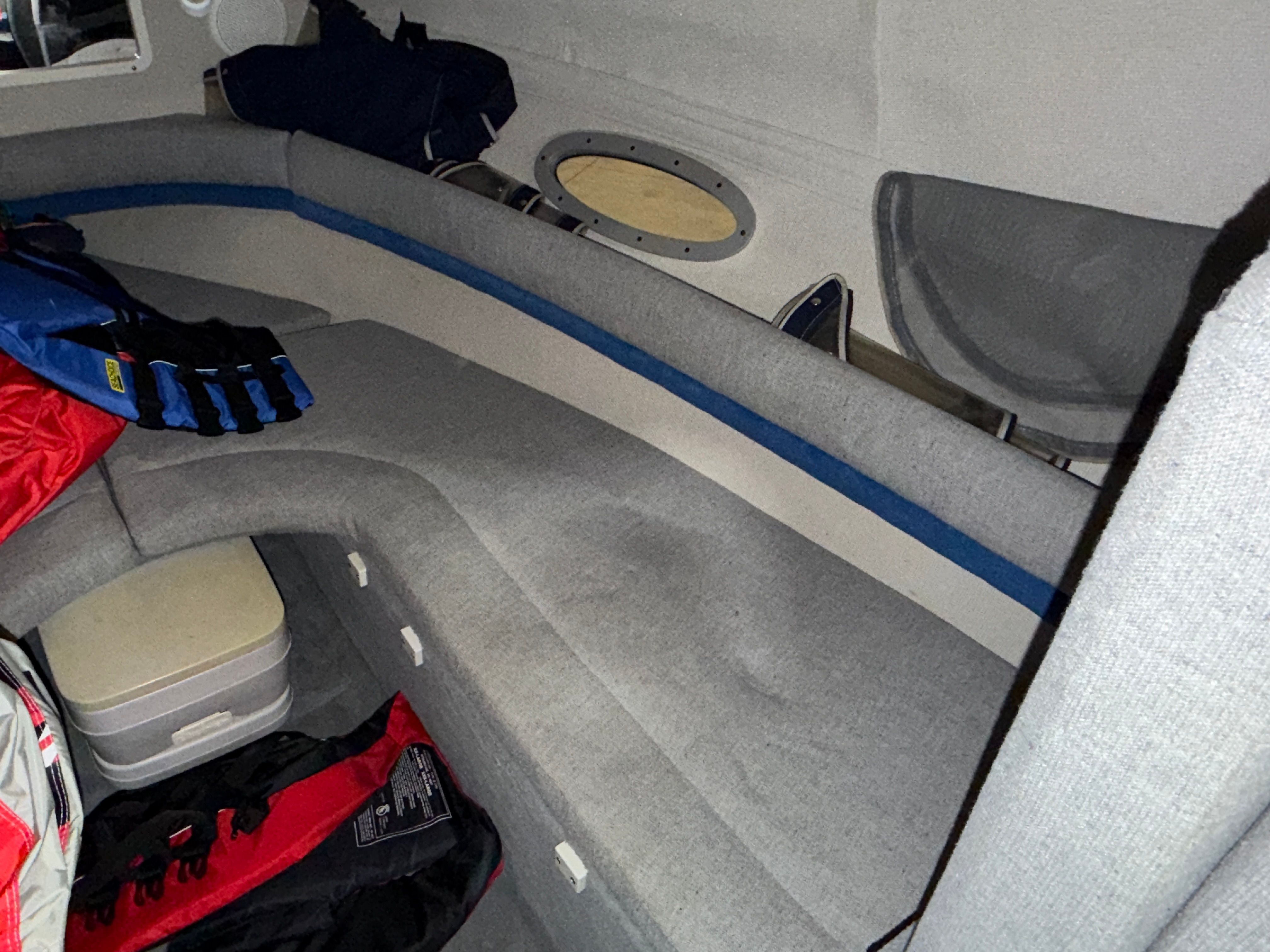 Interior of a 1992 Four Winns 225 Sundowner with gray upholstery and storage space.