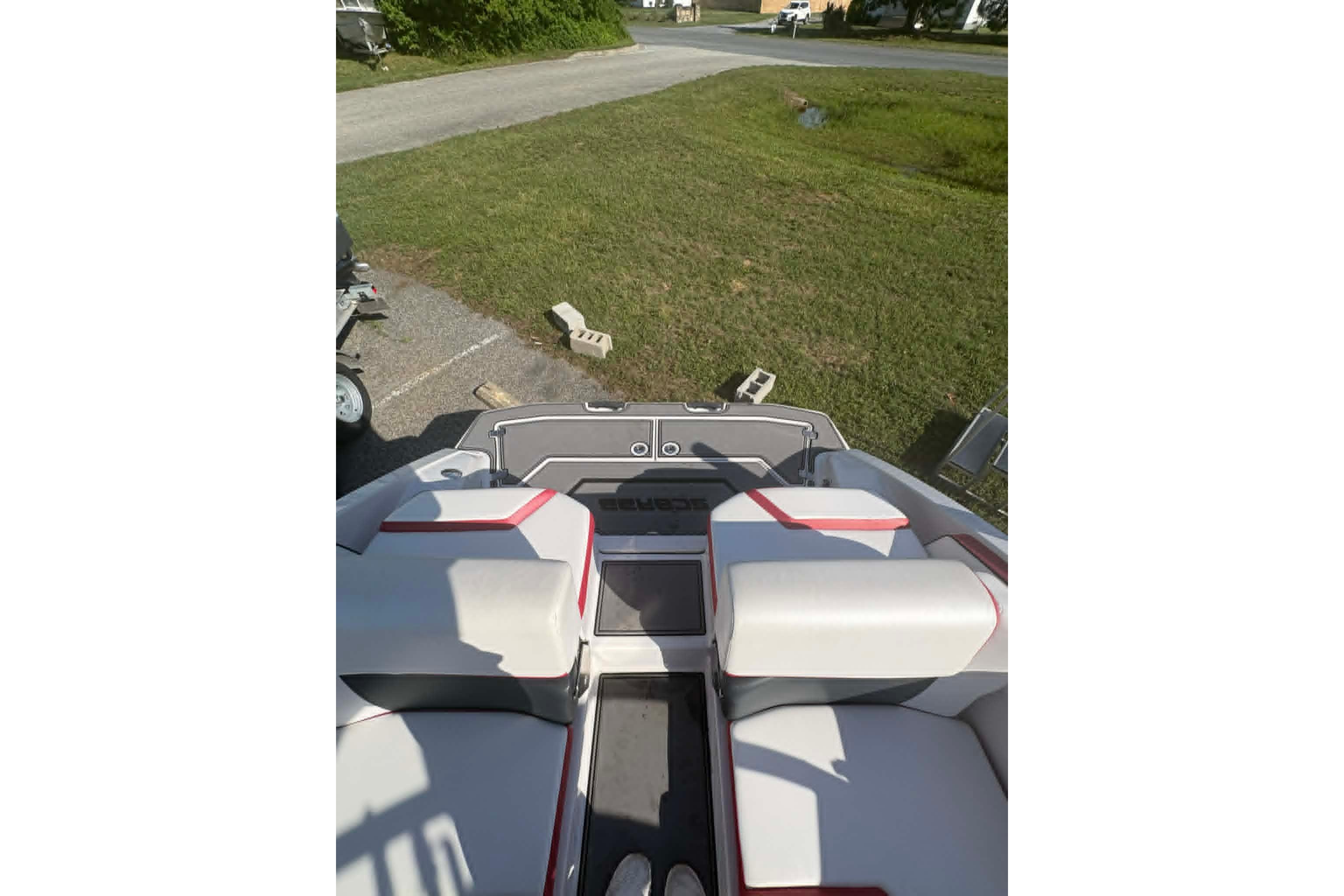 2016 Scarab 255 H.O. Impulse boat interior with white and red seating, parked on grass.
