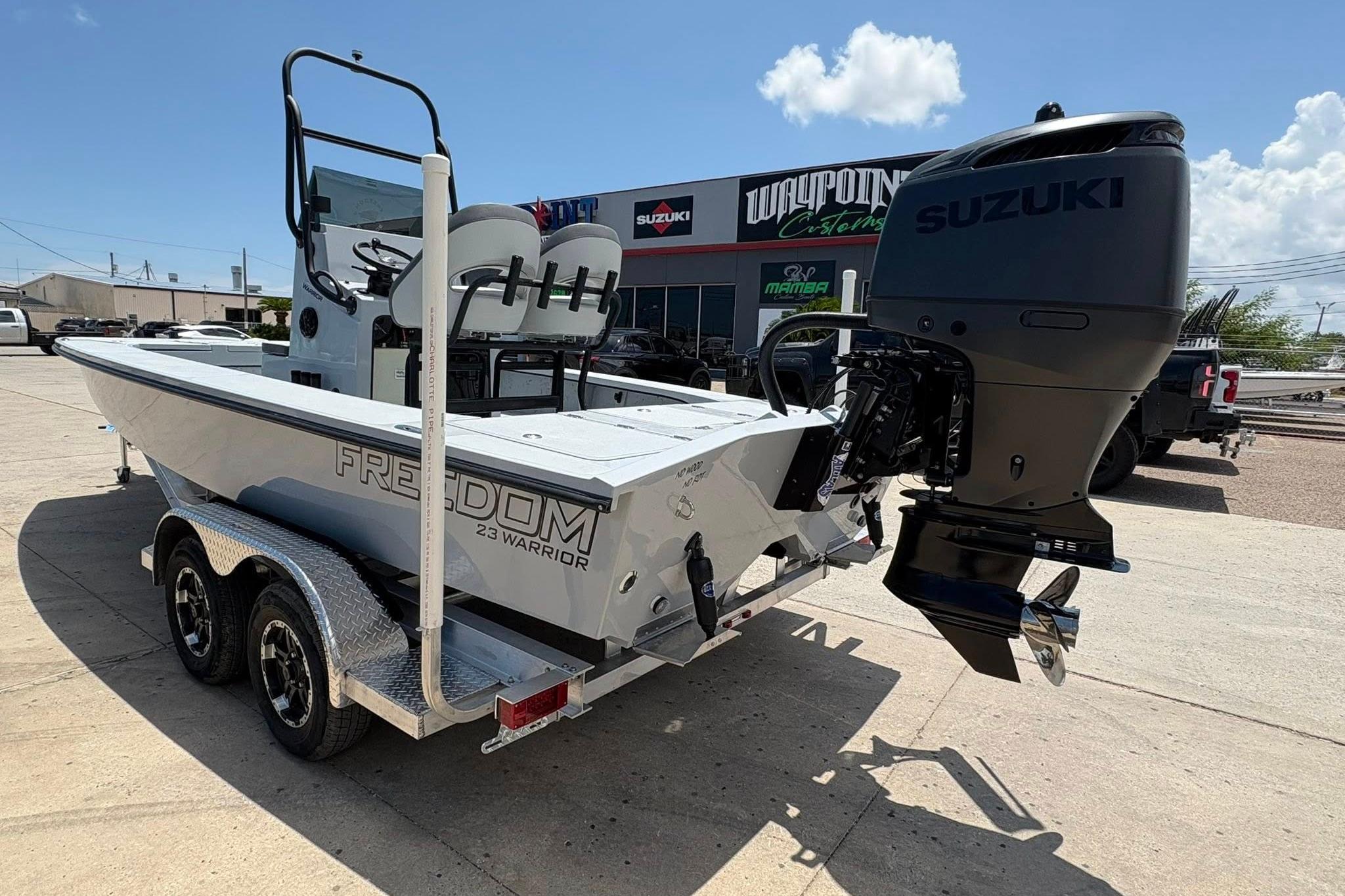 2026 Freedom Boats 23' Warrior with Suzuki engine on trailer, outdoor dealership setting.