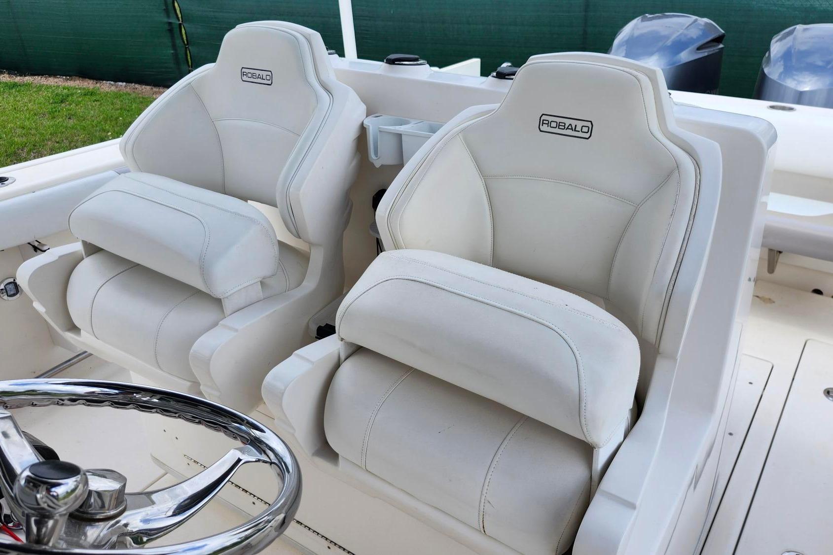 2015 Robalo R300 Center Console boat with white cushioned seats and steering wheel.