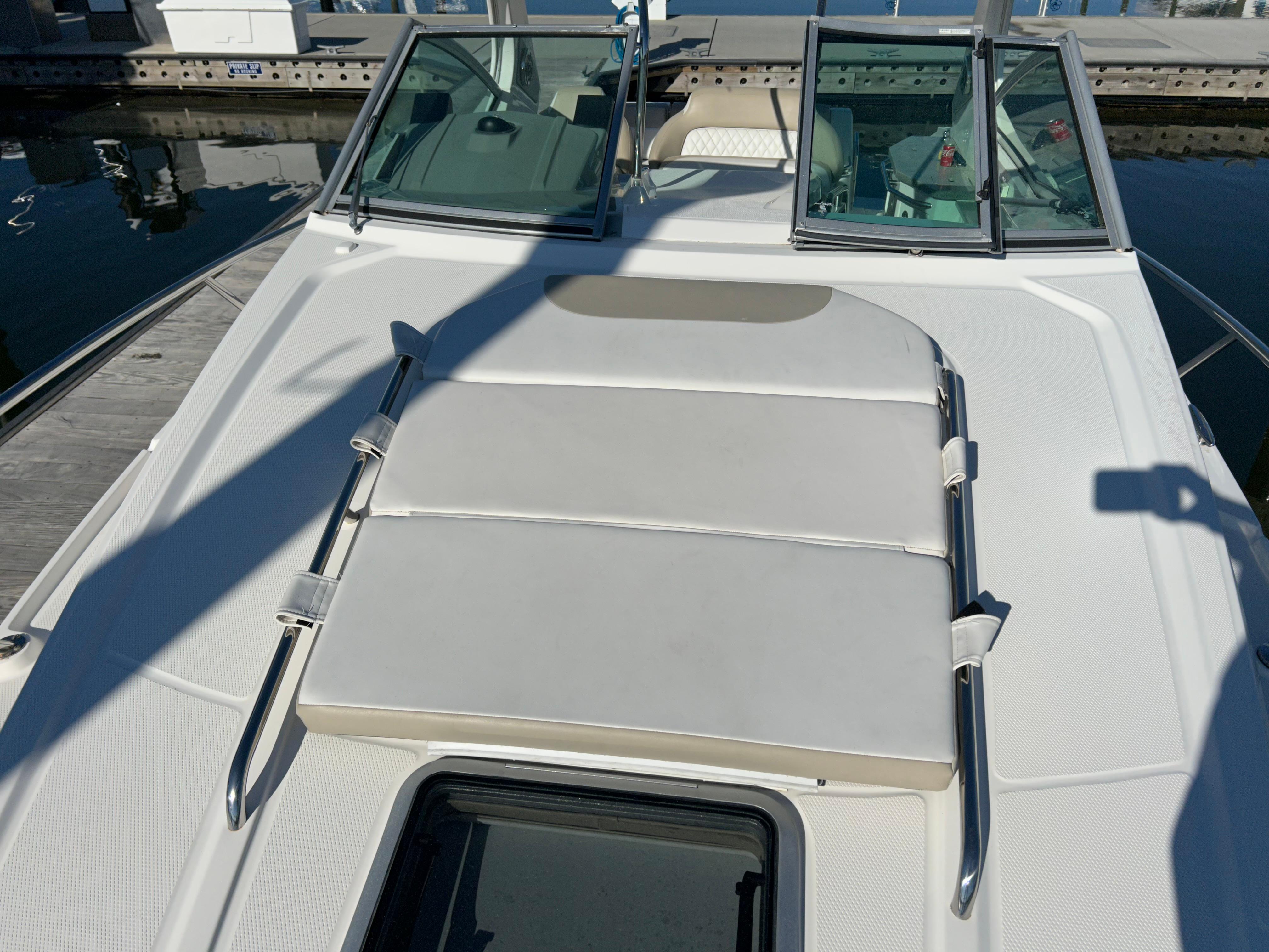 2014 Chaparral 310 Signature boat with sunpad on deck, docked at marina.