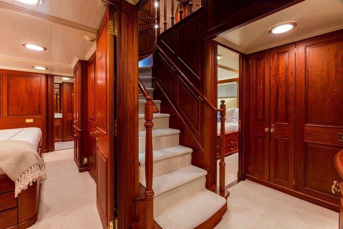 Luxurious wooden interior of a 1997 Palmer Johnson Semi-Displacement yacht, featuring elegant stairs and cabinetry.