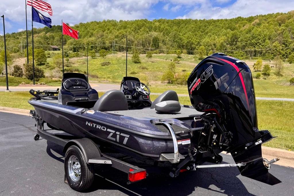 2026 Nitro Z17 boat with powerful engine, parked outdoors near flags and greenery.