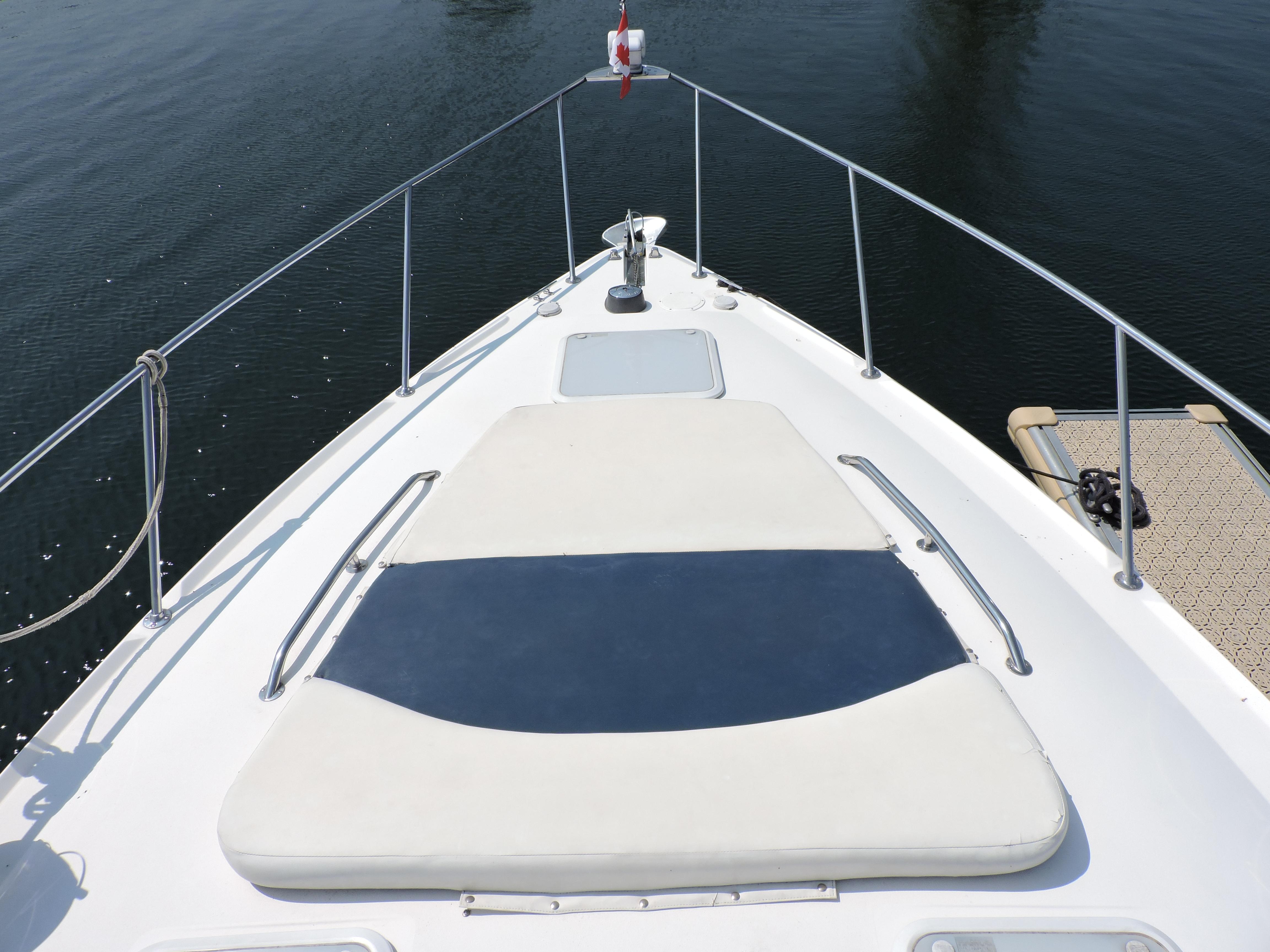 2005 Larson 330 CABRIO boat deck with sun pad, docked on calm water.