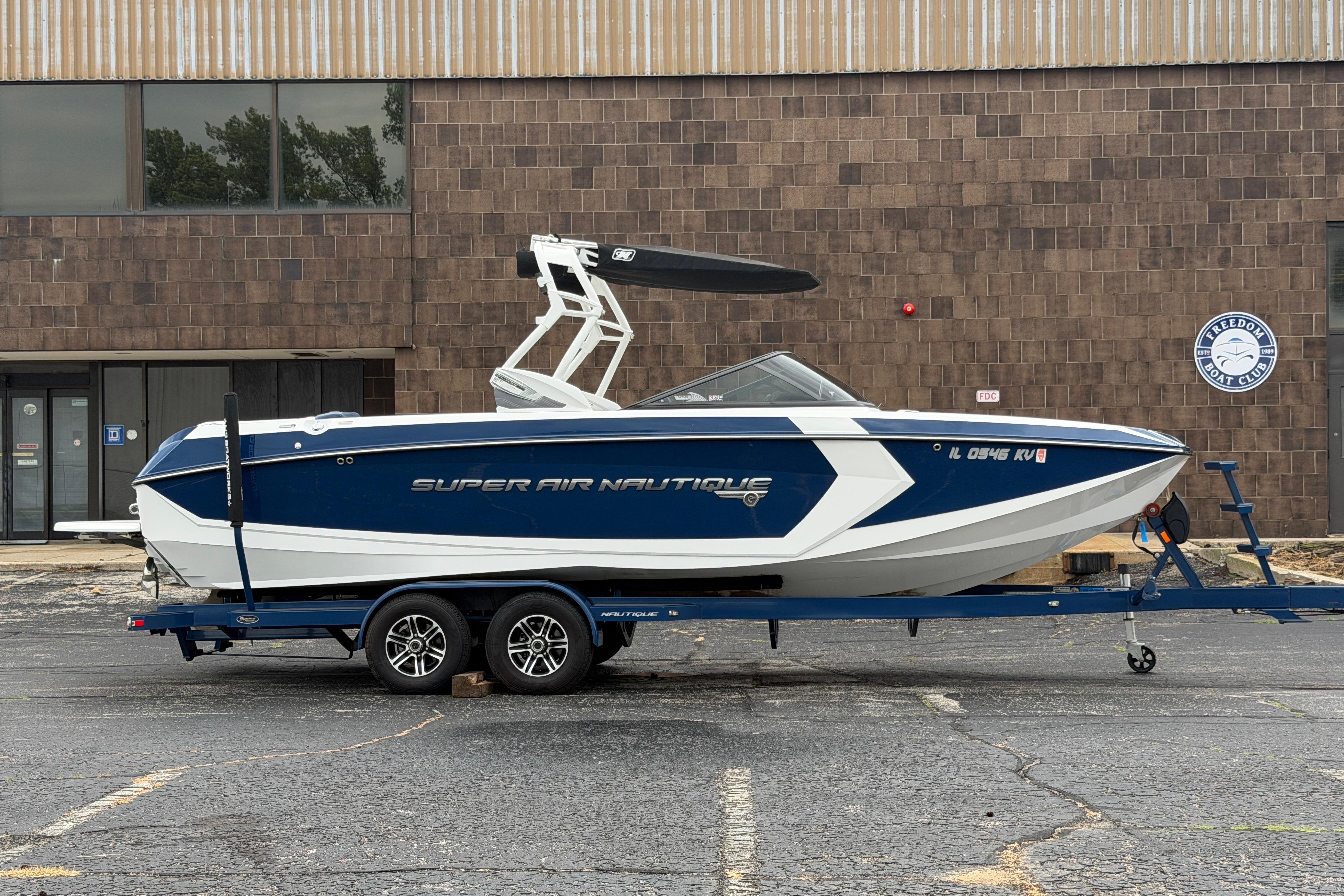 2016 Naitique G25 boat on trailer, parked outside a brick building.