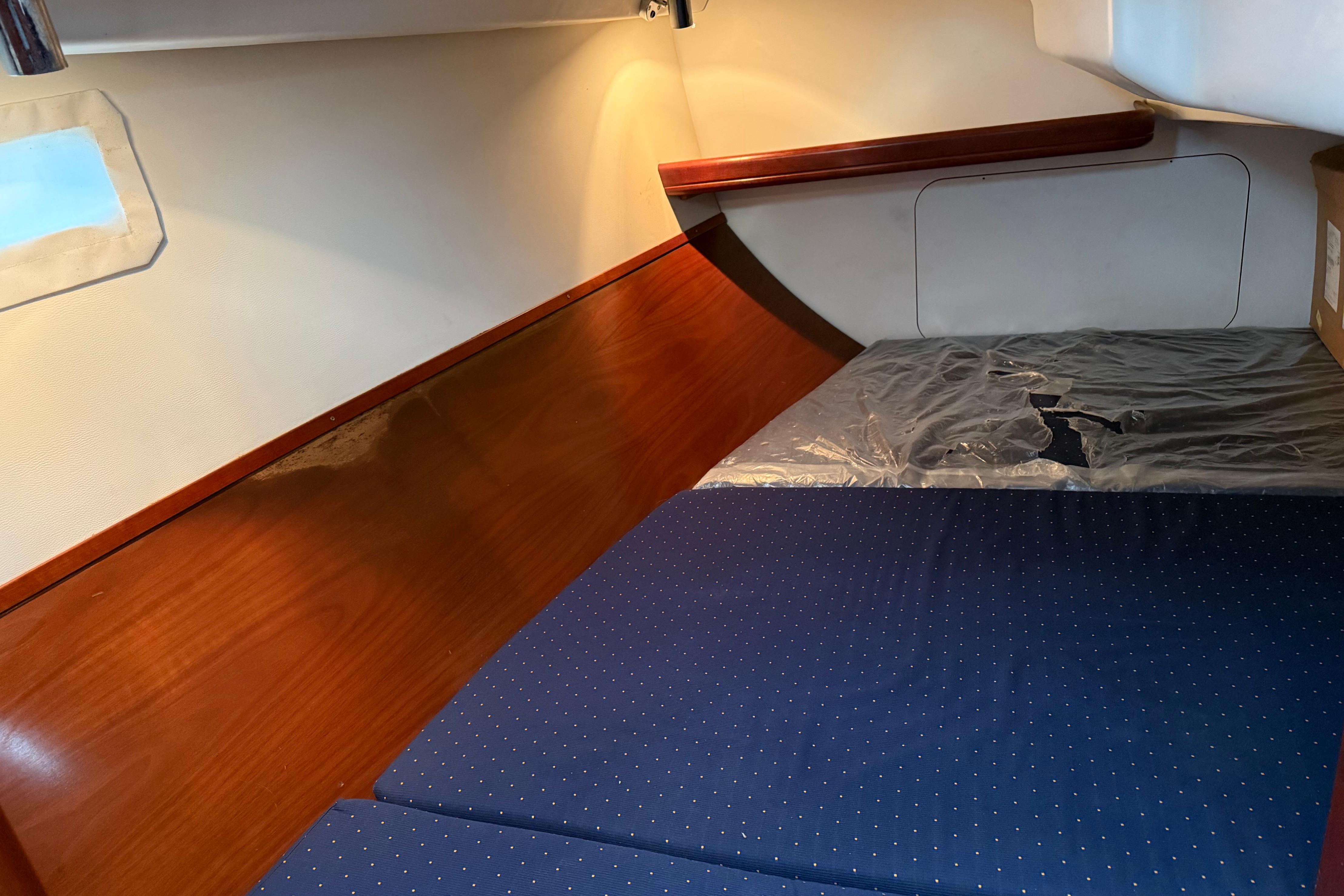 Cozy cabin interior of 2005 Beneteau 331 sailboat with wooden paneling and blue bedding.