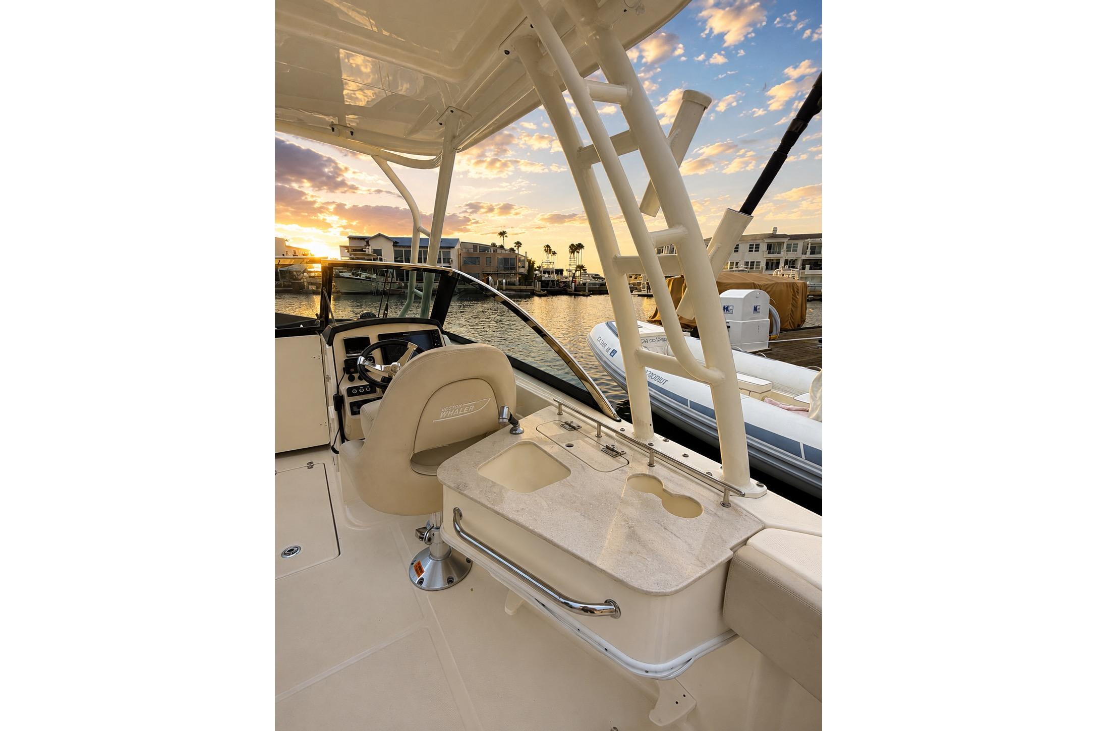 2017 Boston Whaler 230 Vantage boat interior at sunset, featuring helm and seating area.