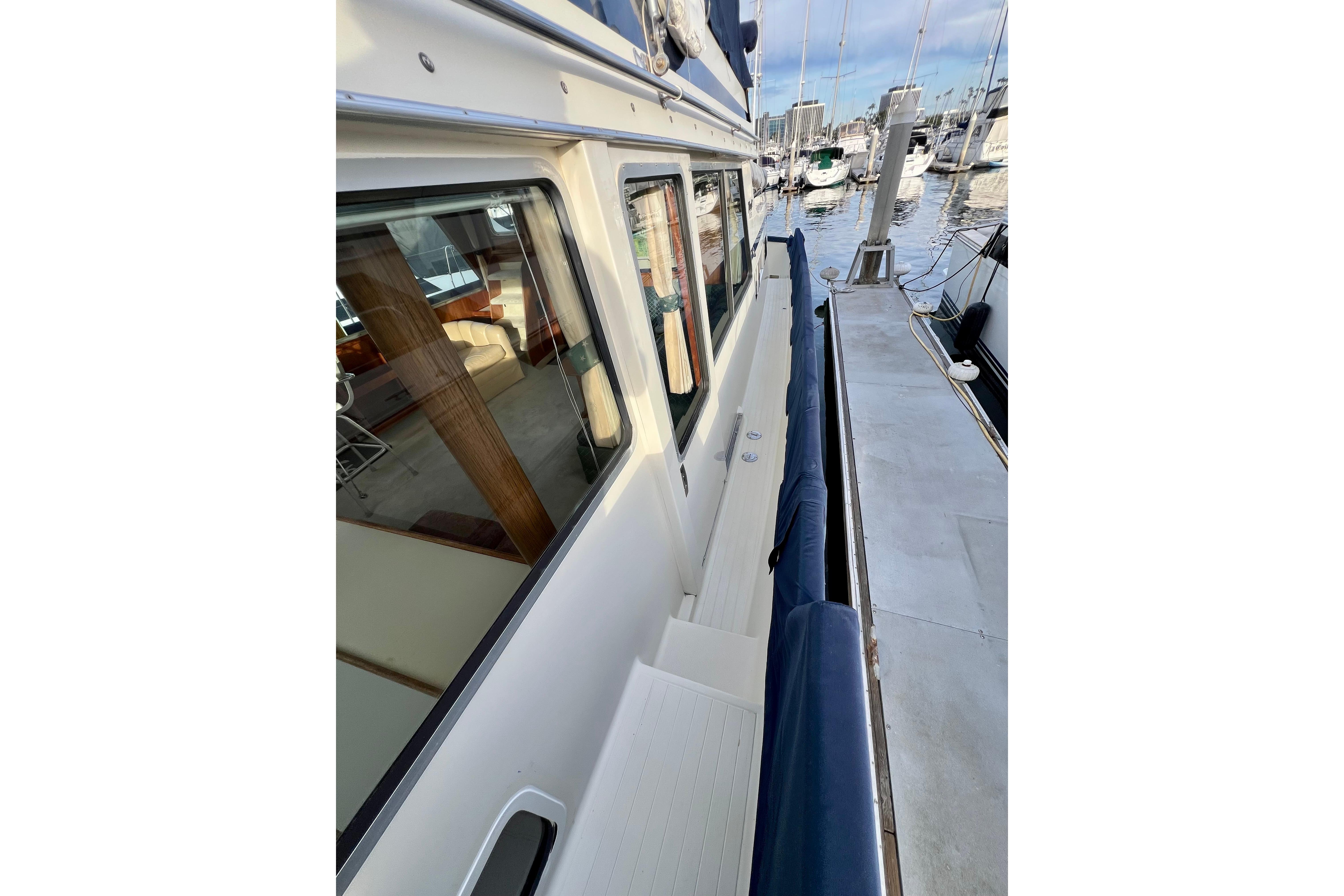1985 Tollycraft 48 Cockpit Motor Yacht docked, showcasing side deck and marina view.