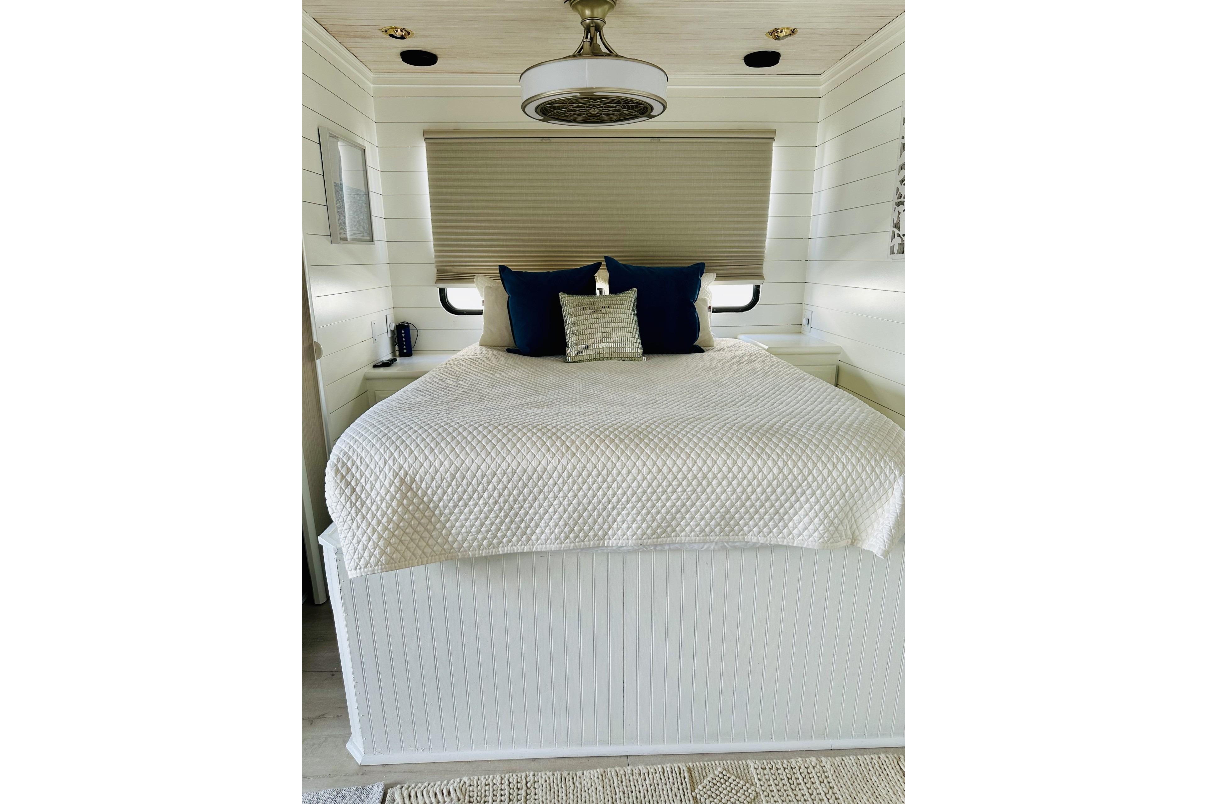 Cozy bedroom interior in 1992 Sumerset 66 houseboat with white bedding and blue pillows.