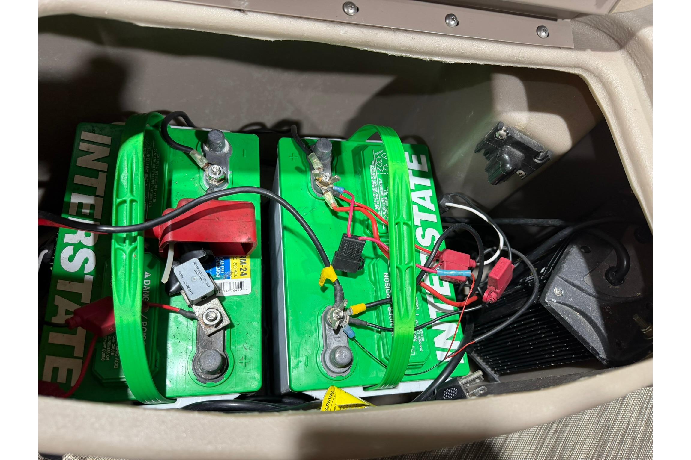 Battery compartment of a 2020 Bennington SX 22 SFX with Interstate batteries and wiring.