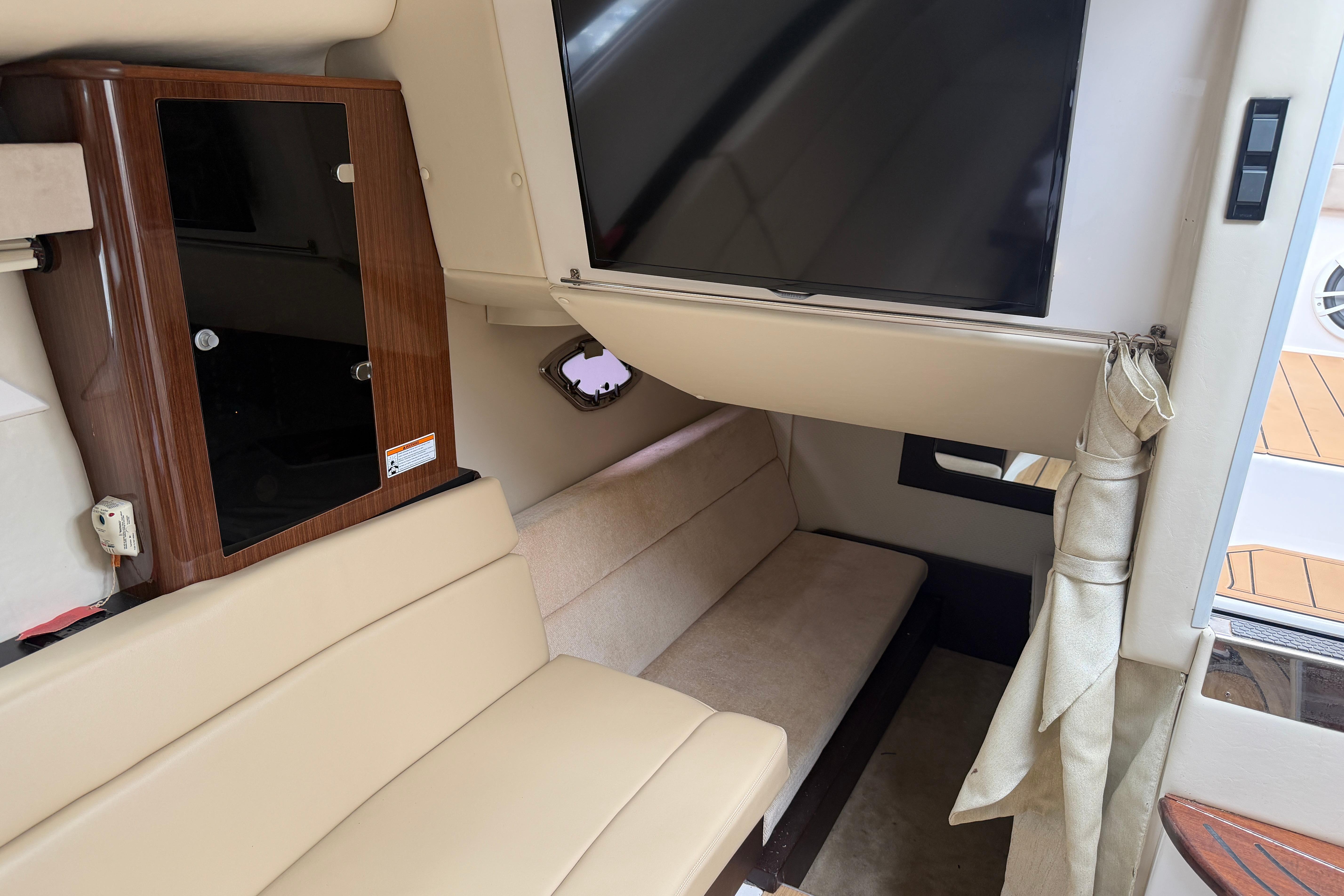 Interior of a 2014 Regal 35 Sport Coupe with beige seating and a mounted TV.
