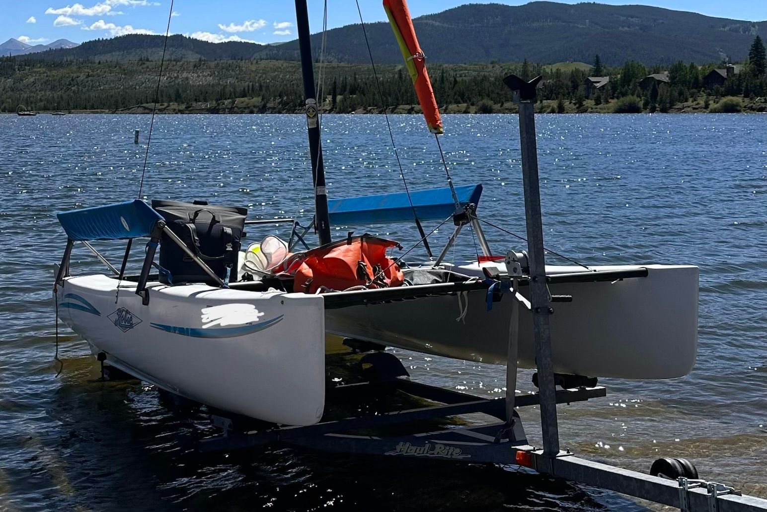 A 2007 Hobie Cat Getaway sits on a trailer by a lake shore.