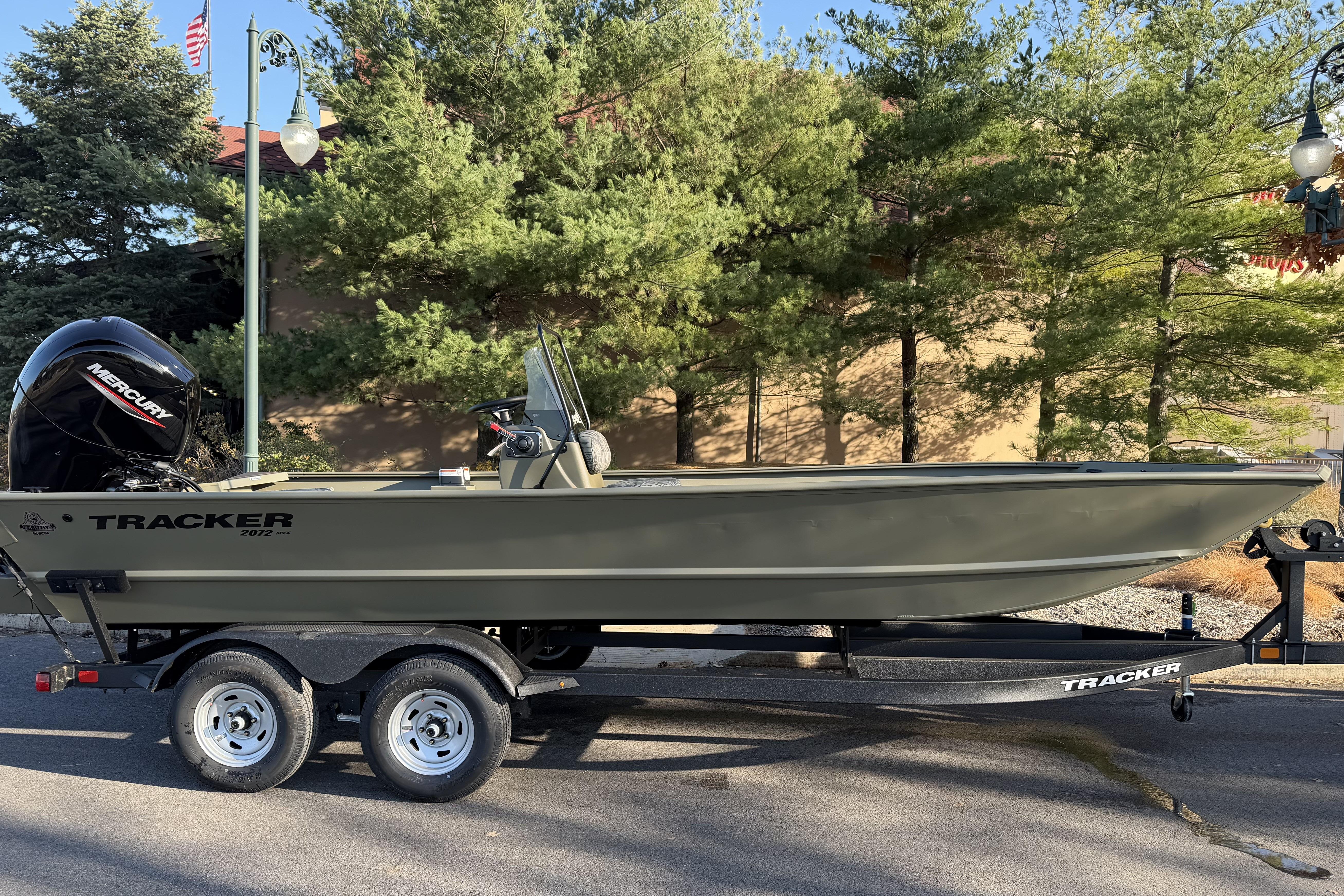 2026 Tracker Grizzly 2072 CC boat on trailer, parked outdoors with trees in background.