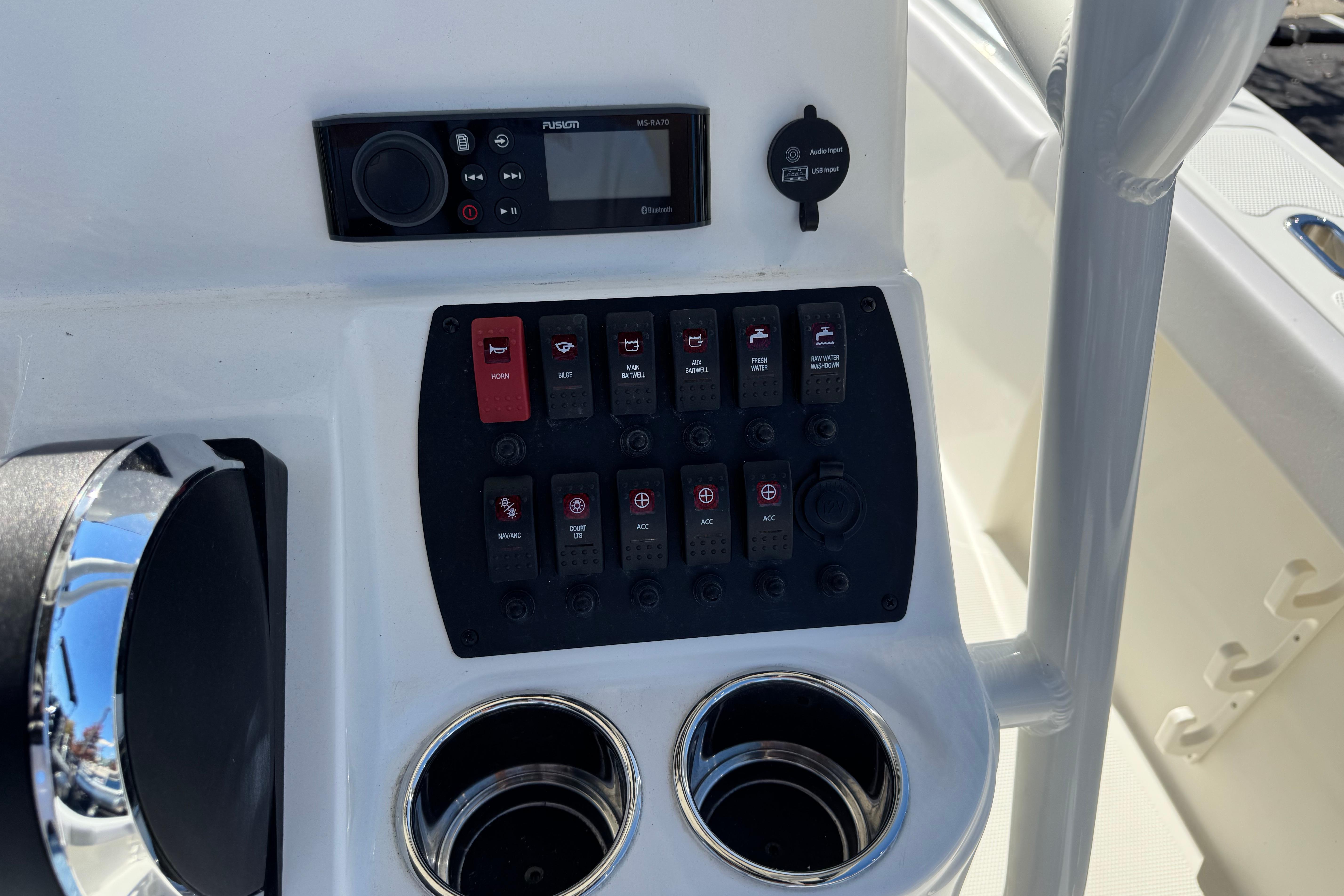 Control panel of 2026 Mako 214 Center Console boat with switches and cup holders.