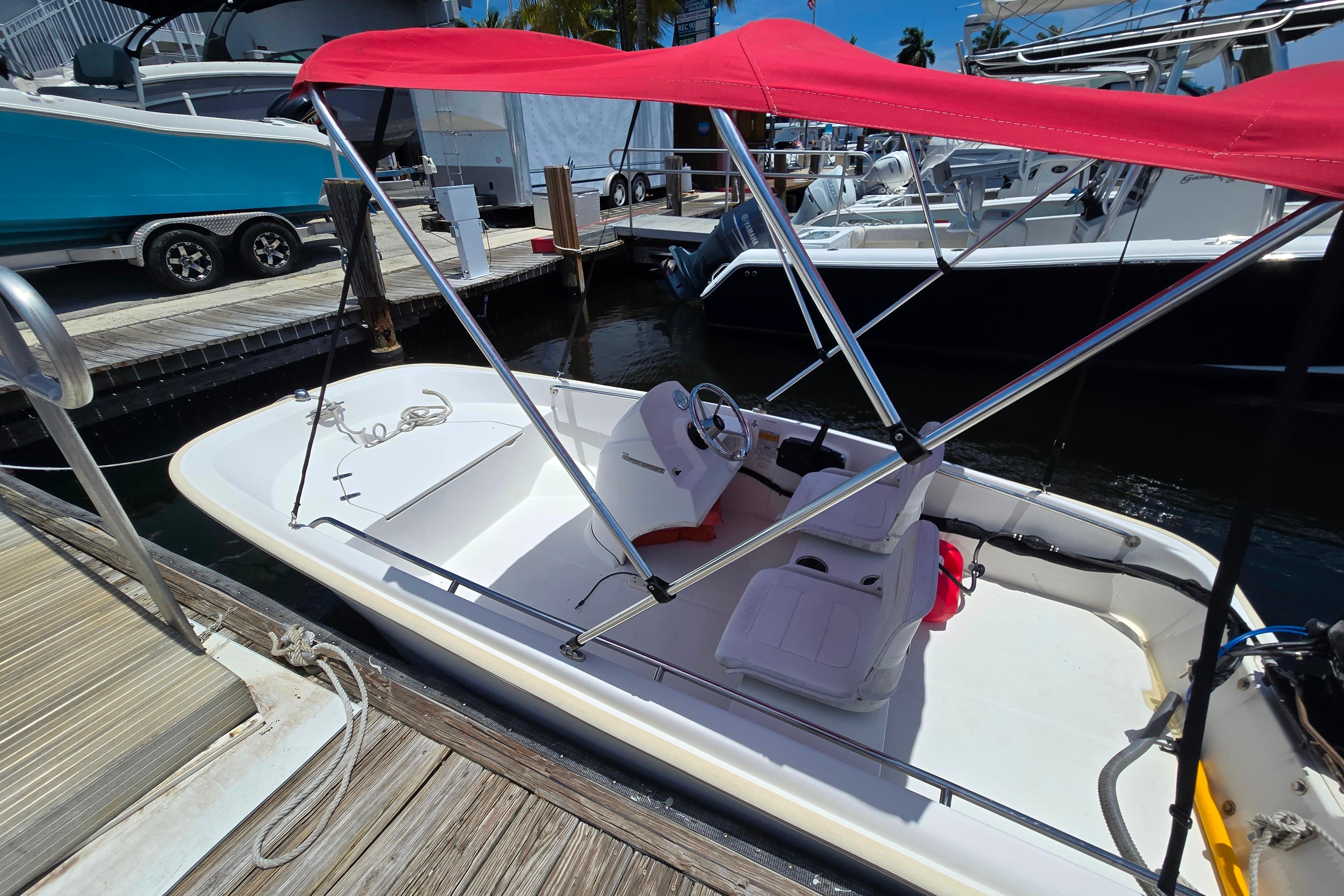 2014 Boston Whaler 13 SS boat with red canopy docked at marina.