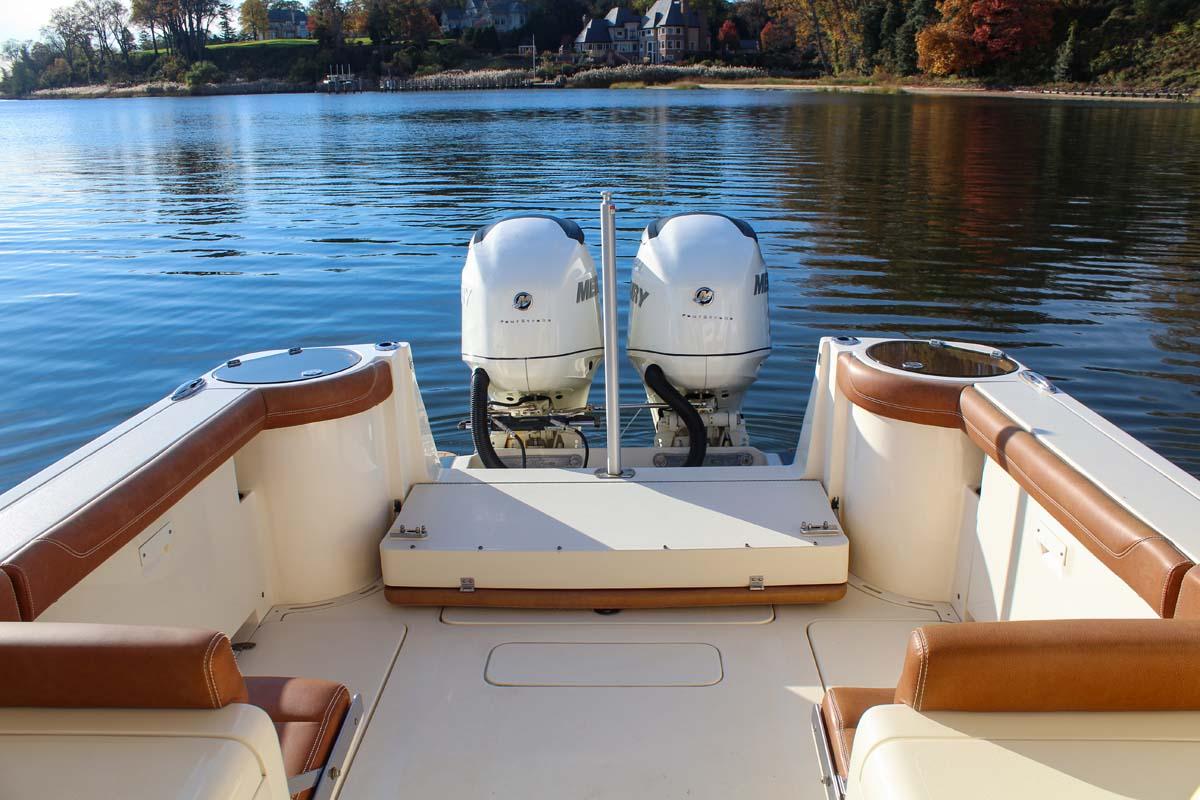 2018 Scout 275 Dorado boat with twin outboard engines on a calm lake.
