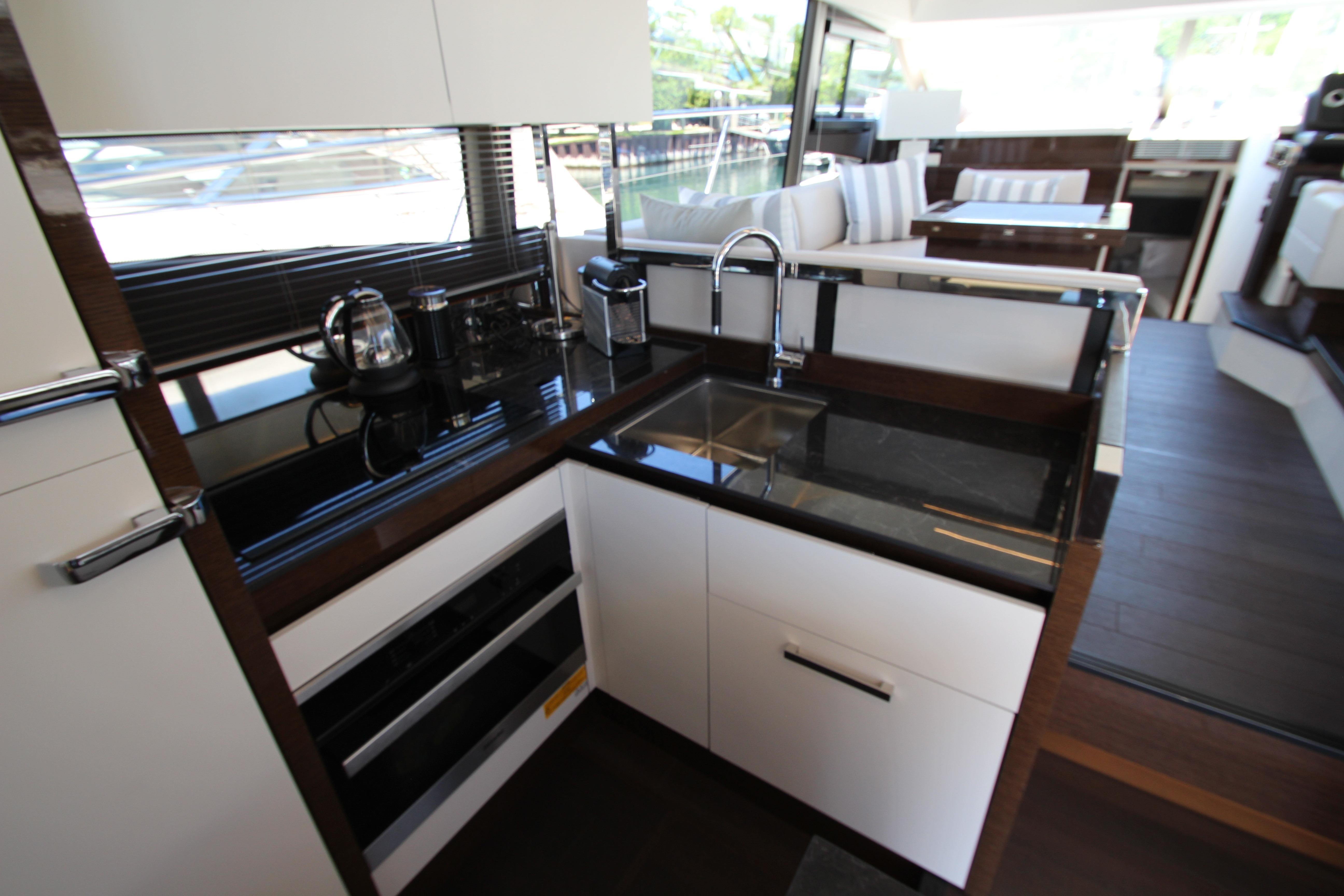 Modern kitchen interior on 2022 Prestige 520 yacht, featuring sleek countertops and stainless steel appliances.