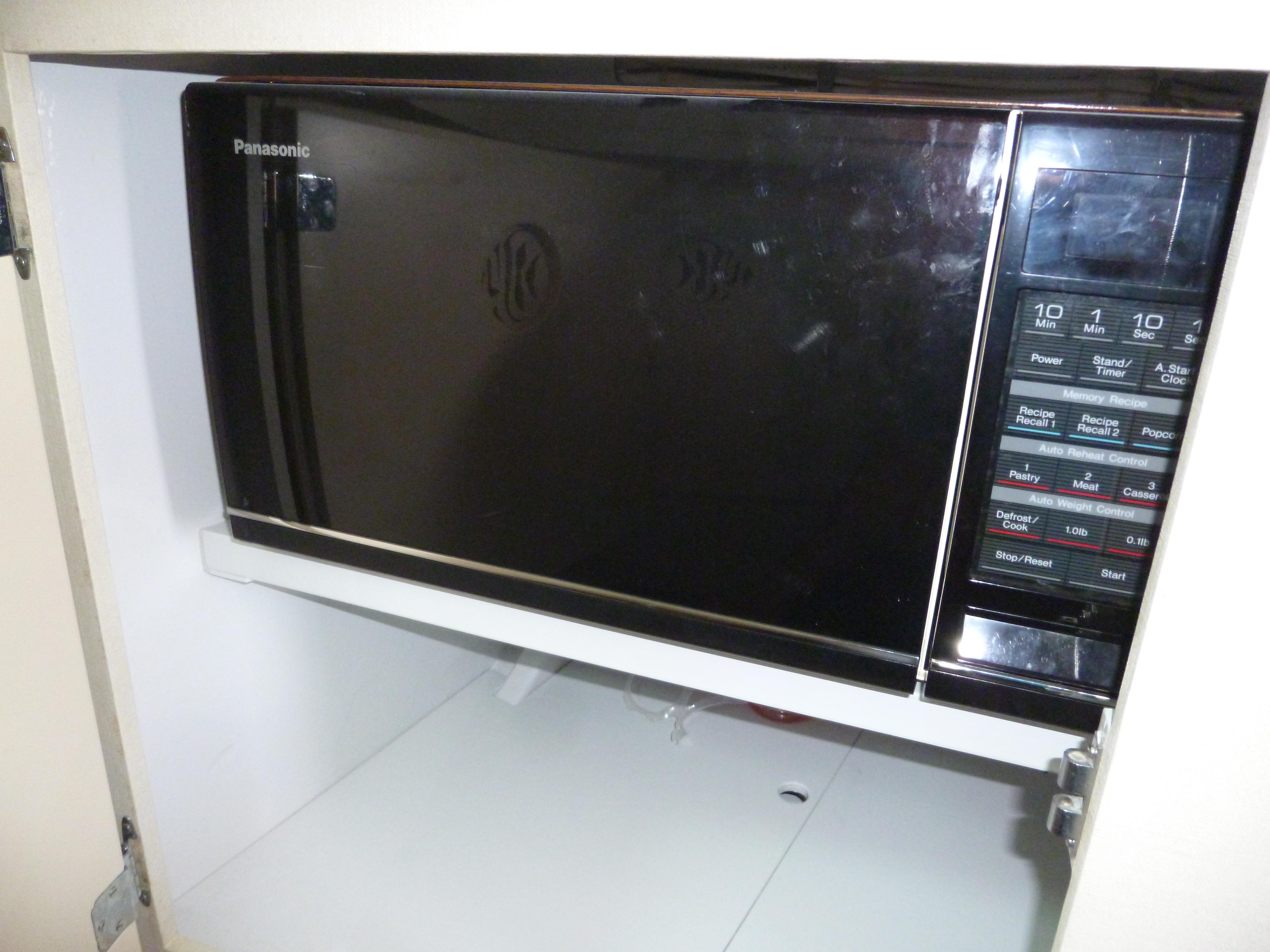 Panasonic microwave oven with digital controls, installed in a kitchen cabinet.