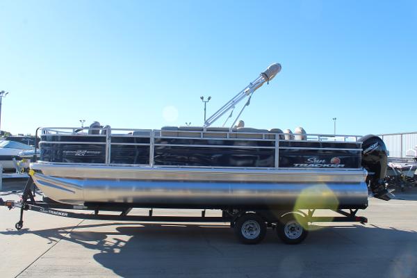 2025 Sun Tracker Fishin' Barge 22 DLX pontoon boat on trailer, sunny day.