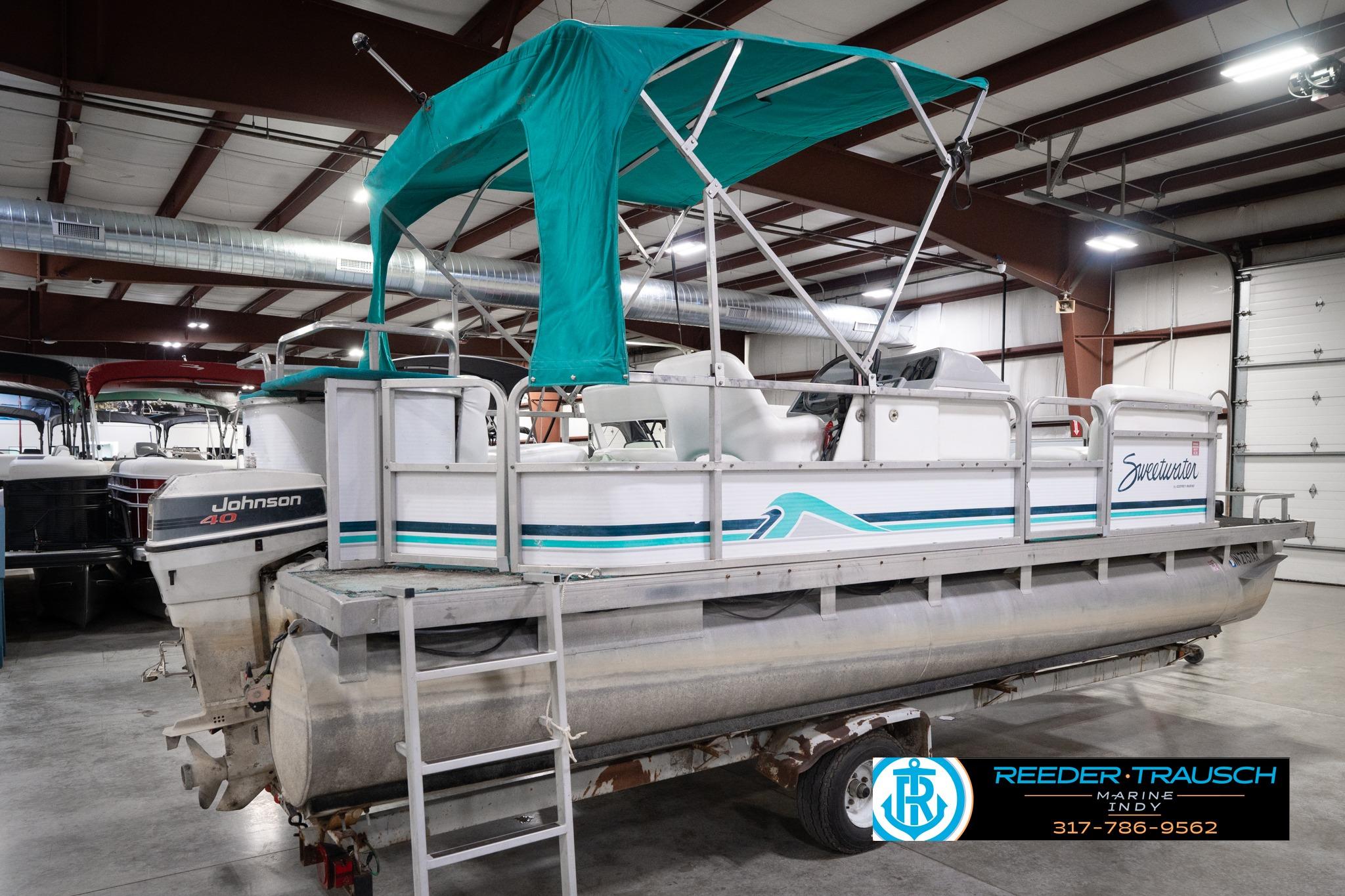 1992 Godfrey Sweetwater pontoon boat with Johnson 40 engine in indoor storage.
