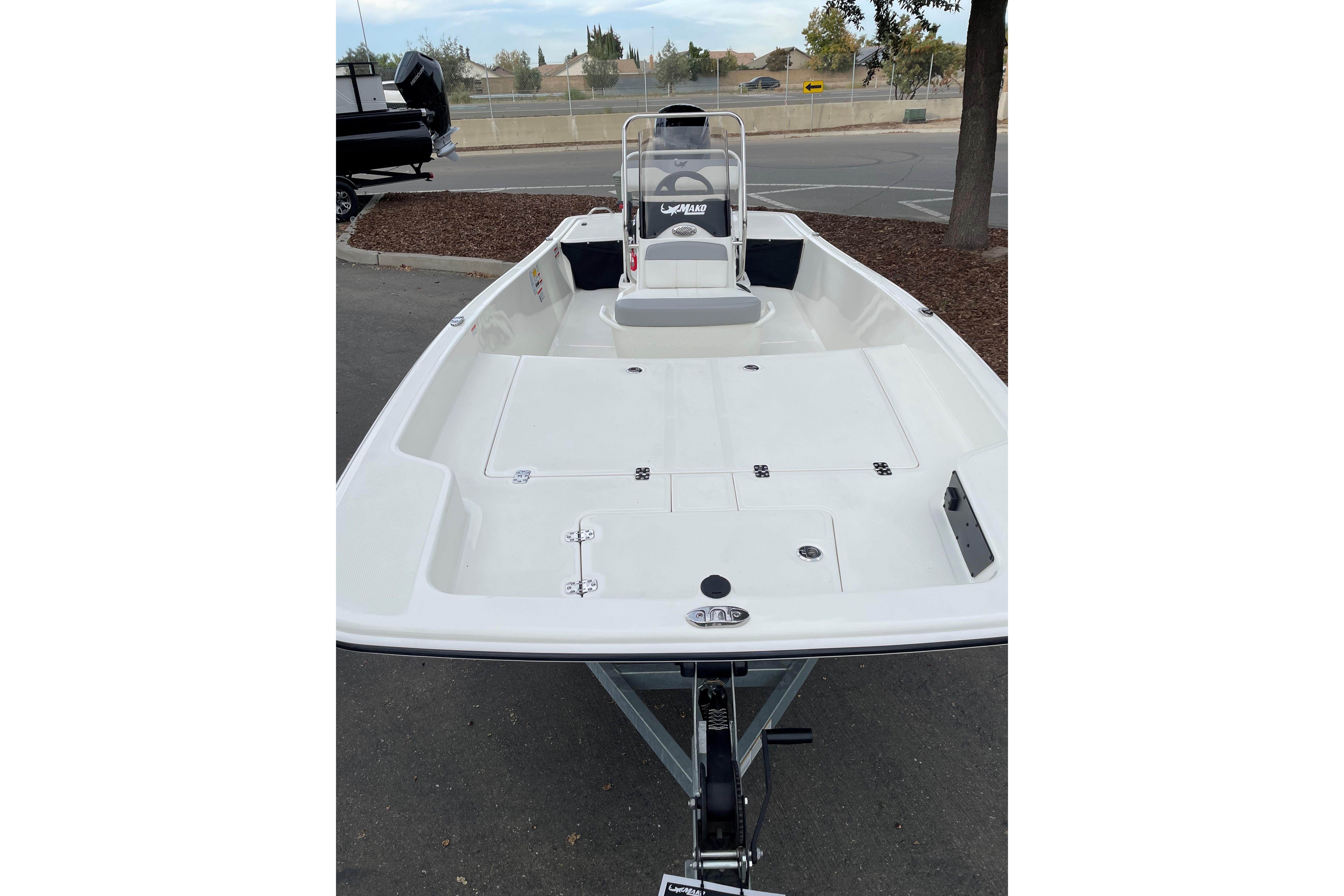2025 Mako Pro Skiff 17 CC boat, white deck, parked outdoors.