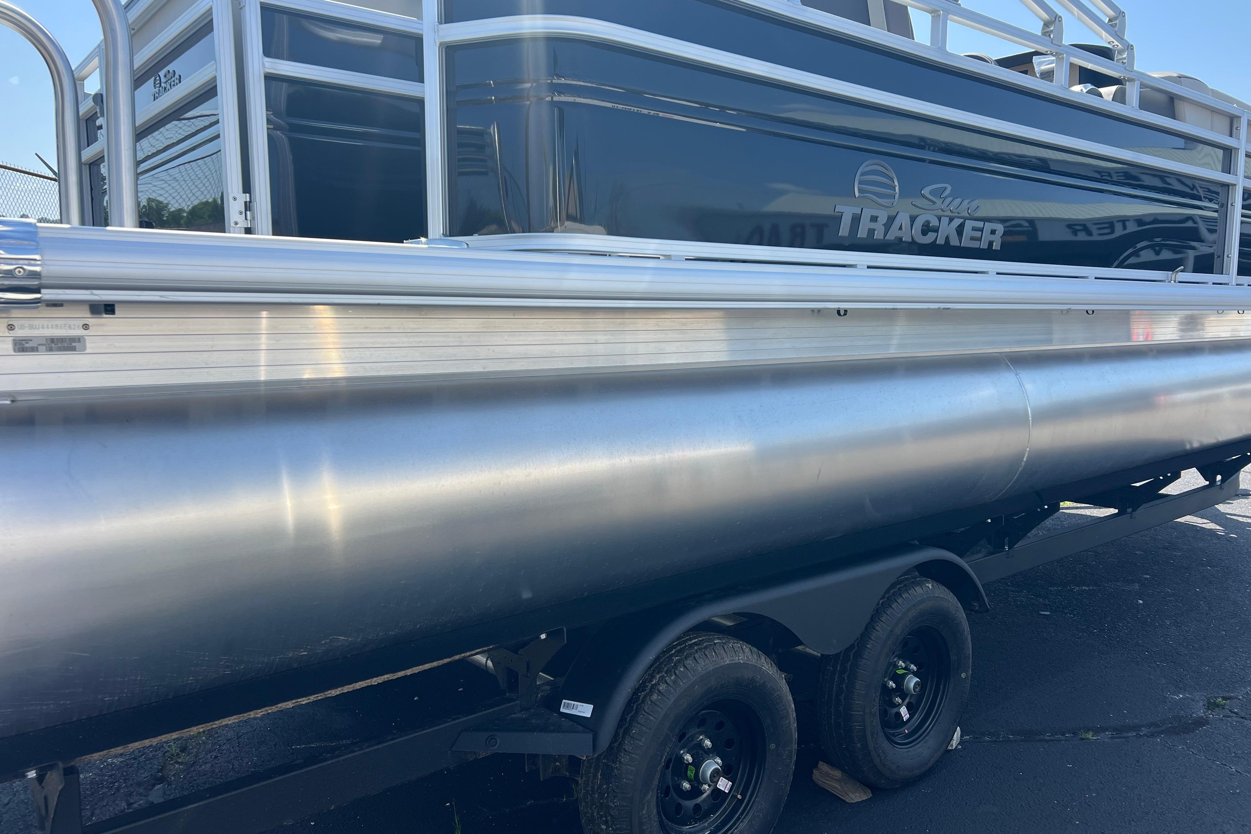 2026 Sun Tracker Fishin' Barge 22 DLX pontoon boat on trailer, side view.